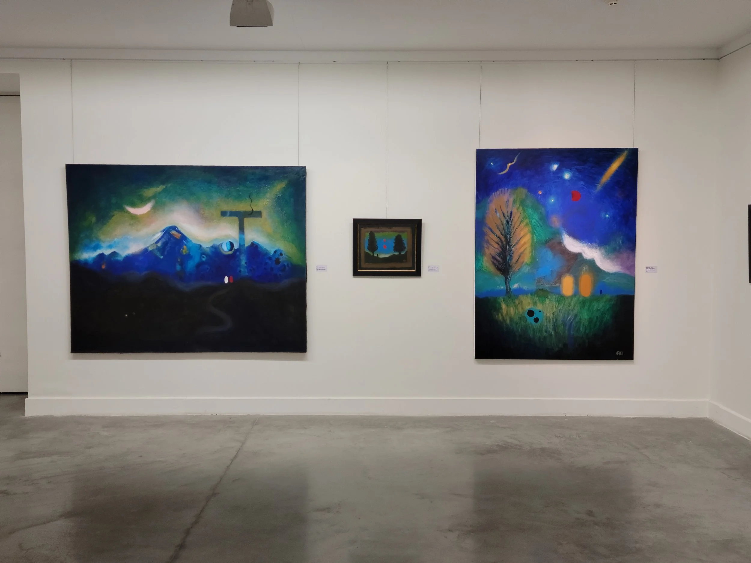 Three paintings of Anton Balanchivadze on a white gallery wall, one large landscape painting on the left, a small landscape painting in the center, and another large landscape painting on the right.
