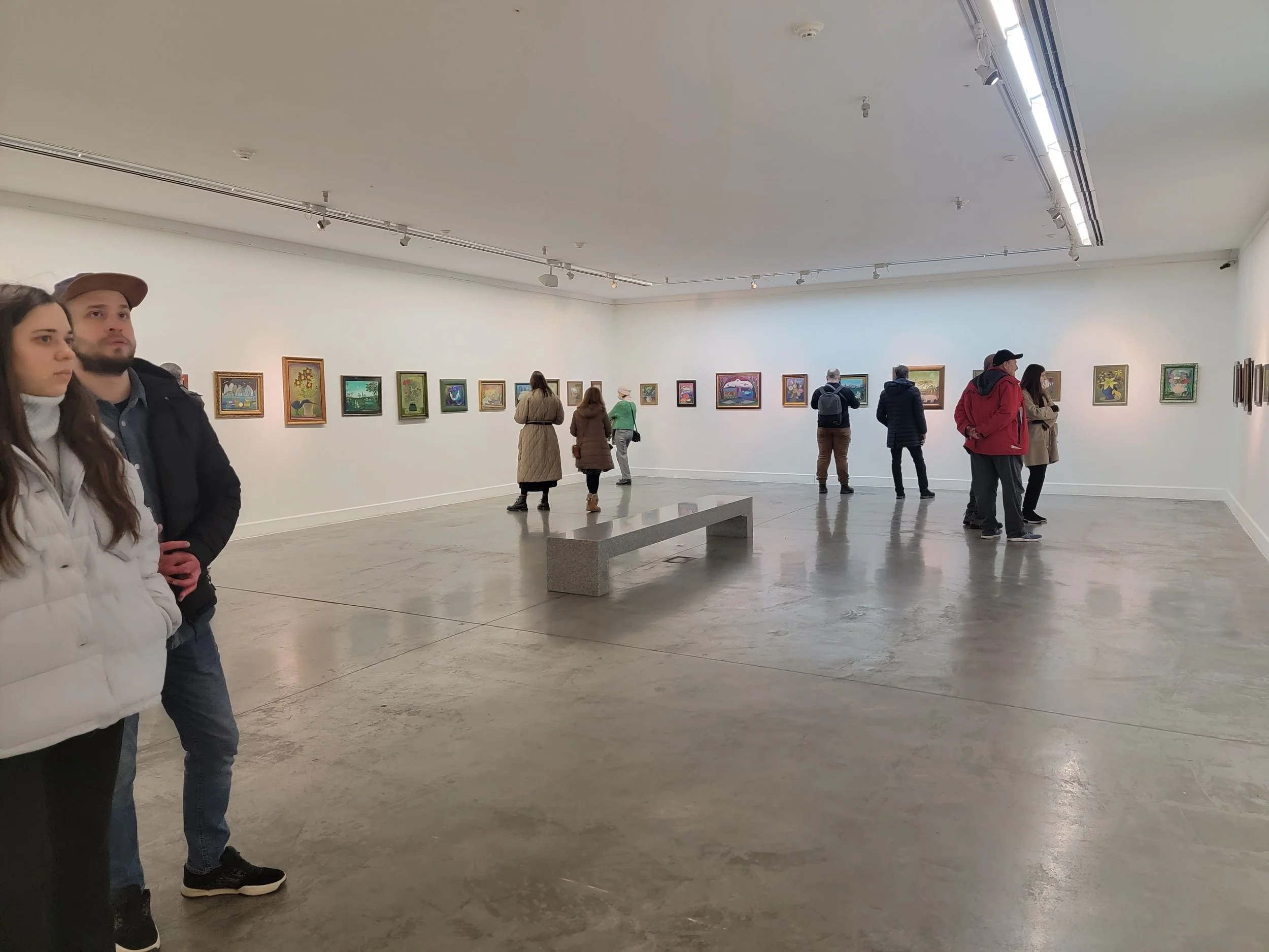 People viewing artwork in a gallery with white walls and a concrete floor