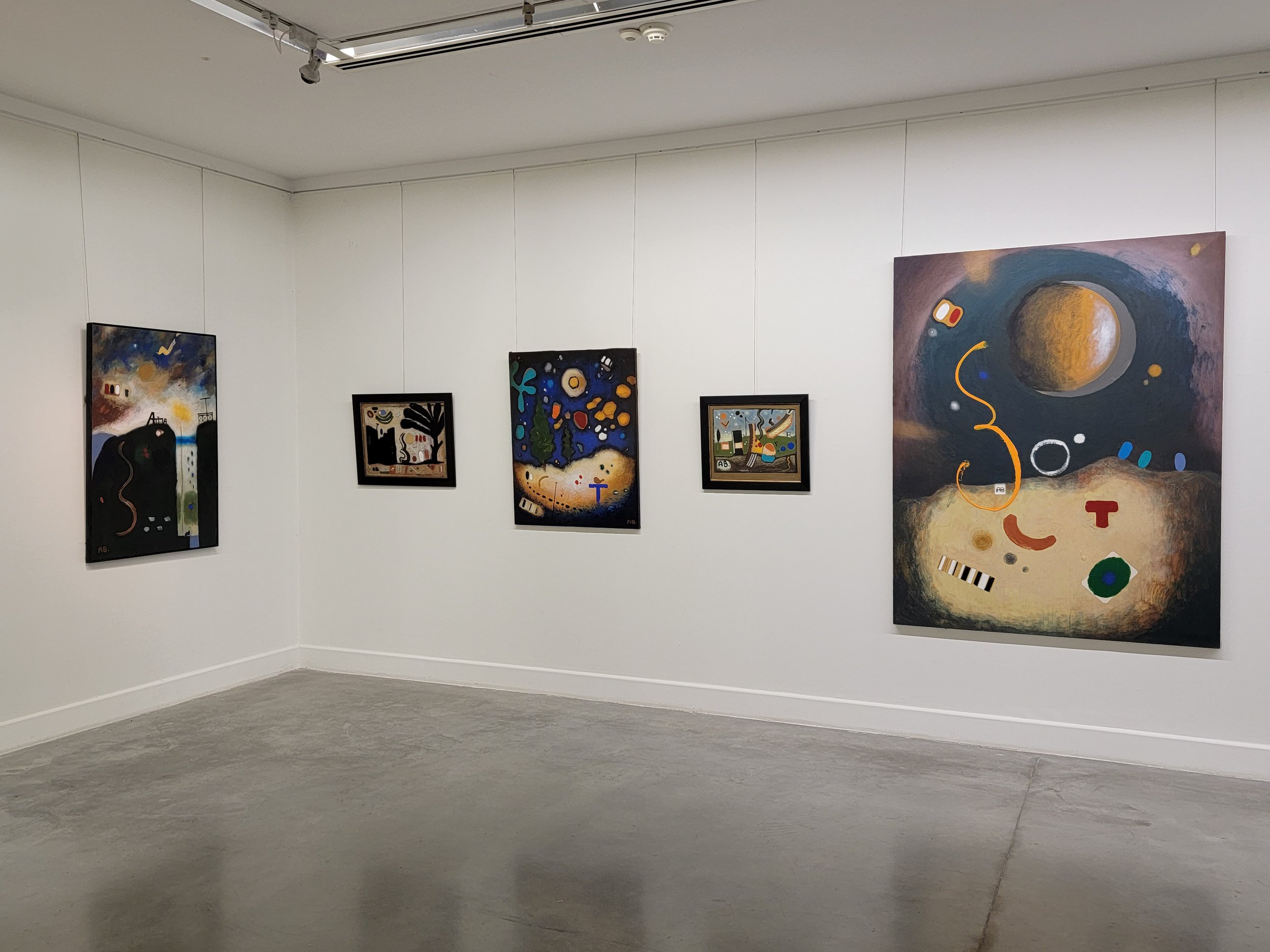 An art gallery with five abstract paintings on white walls, featuring a mix of dark, vibrant, and pastel colors.