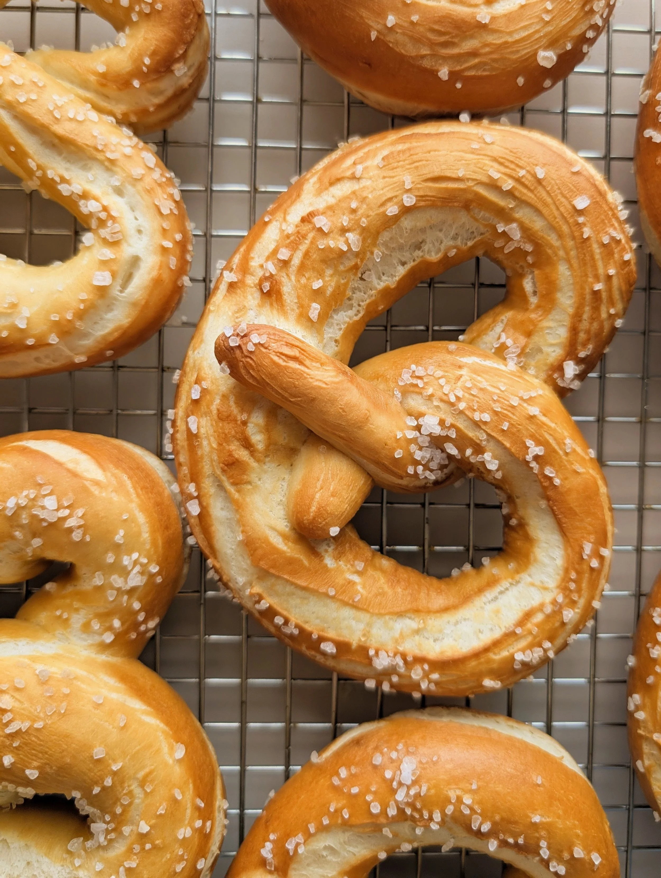 Close-up of salted soft pretzels on a wire rack.
