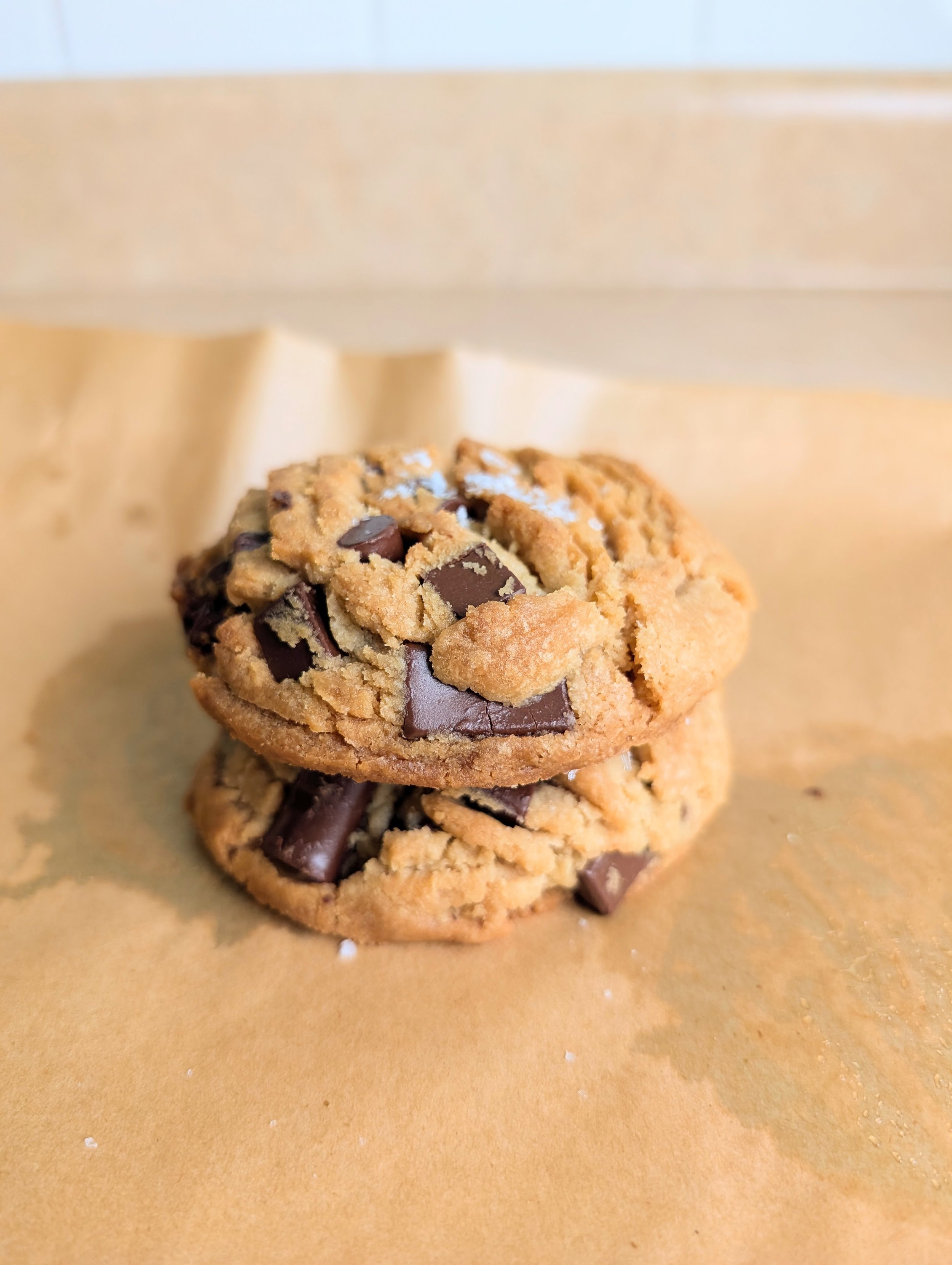 Close-up of chocolate chip cookies on a brown paper surface.