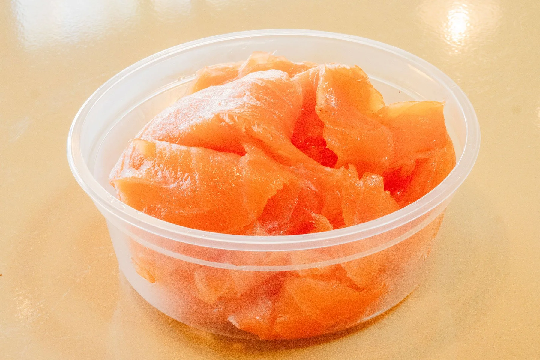 Sliced pieces of fresh salmon fish in a clear plastic container.