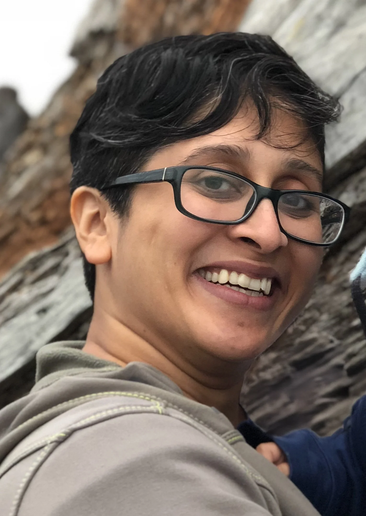 Bhav Nancherla smilling at camera with dark framed glasses