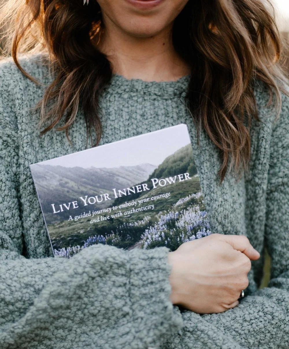 Person holding a booklet titled "Live Your Inner Power" with a landscape cover of mountains and greenery.