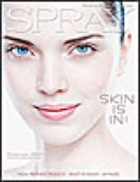 Close-up of a woman's face with clear skin and blue eyes, with text reading 'SKIN IS IN' and 'SPRAY'.