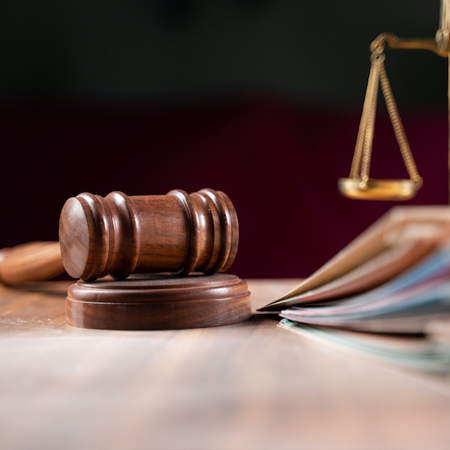 Gavel, legal documents, and a scale of justice on a desk.