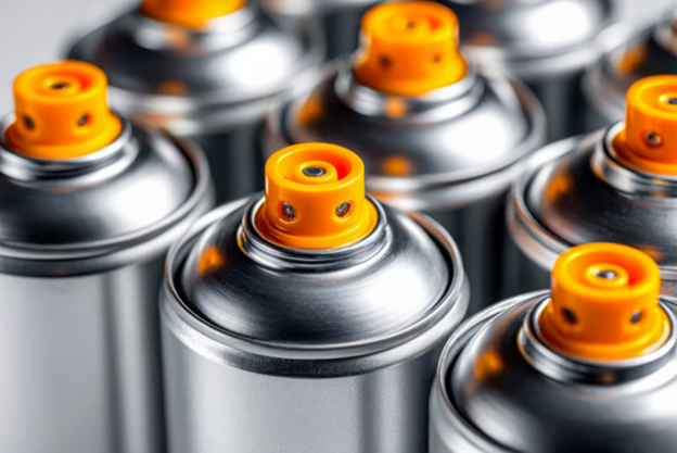 Close-up of multiple aerosol spray cans with orange nozzles, arranged together.