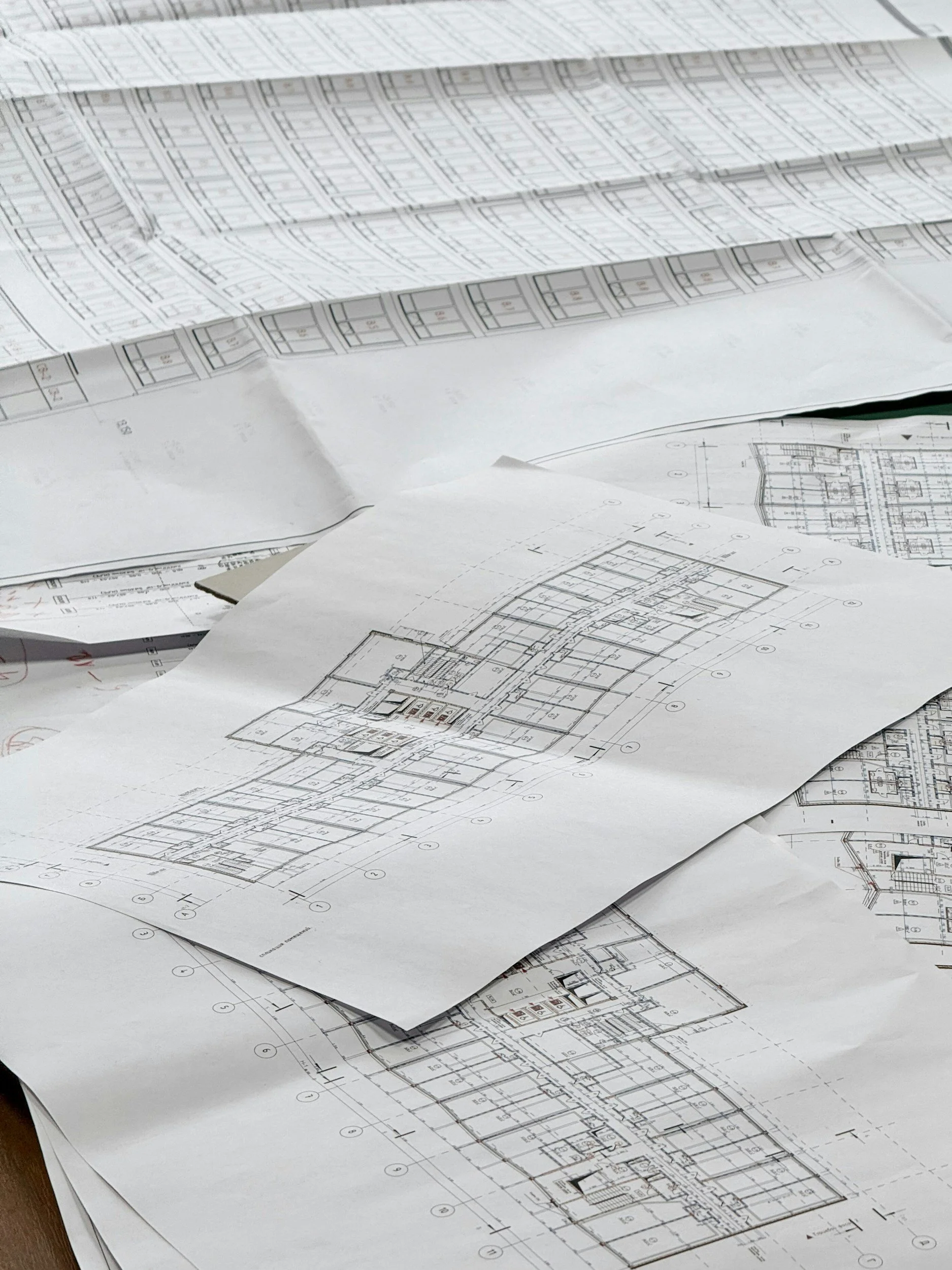 Architectural blueprints and floor plans spread out on a desk.
