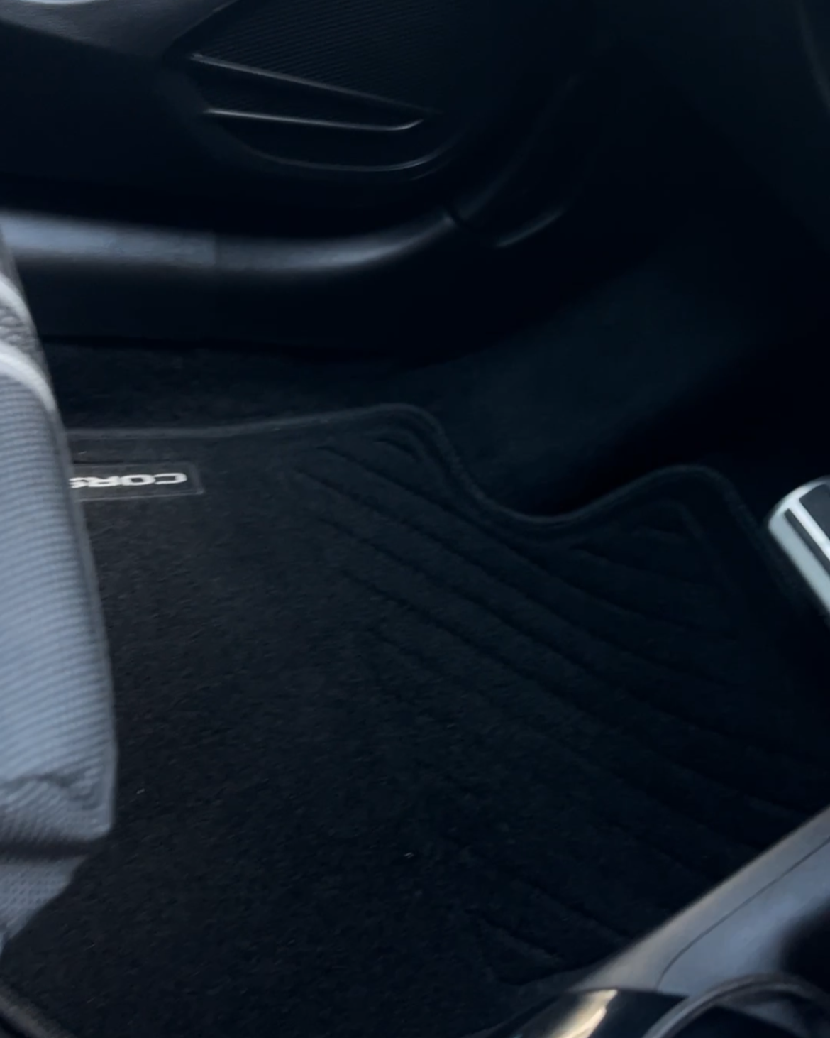 Innenraum eines Autos, Blick auf das Fußbodenbereich mit Fußmatte und Pedalen.