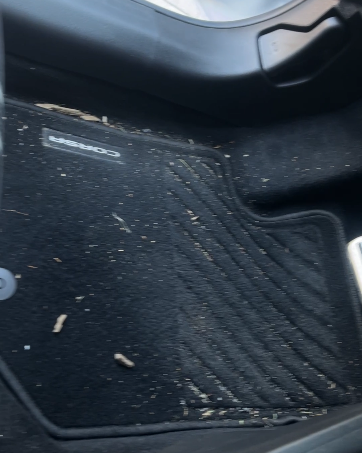 Autofußmatte in einem Auto, auf der Schlamm und Schmutz liegen.