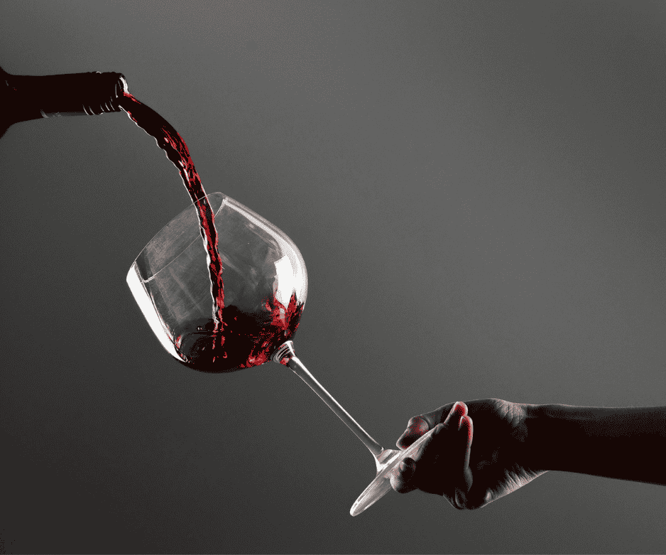 Red wine being poured into a large wine glass