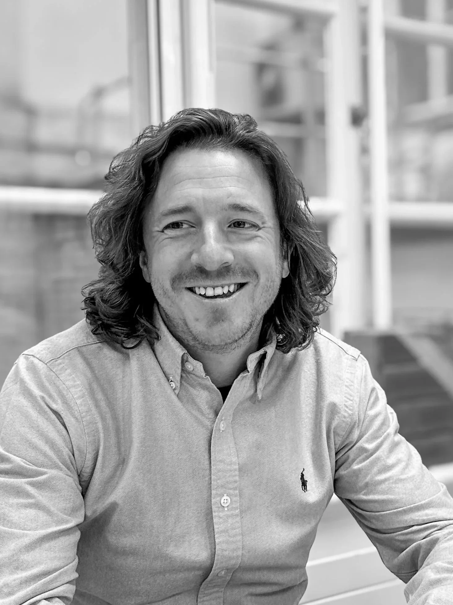 Bradley Roast sitting in an indoor setting with blurred background shelves.