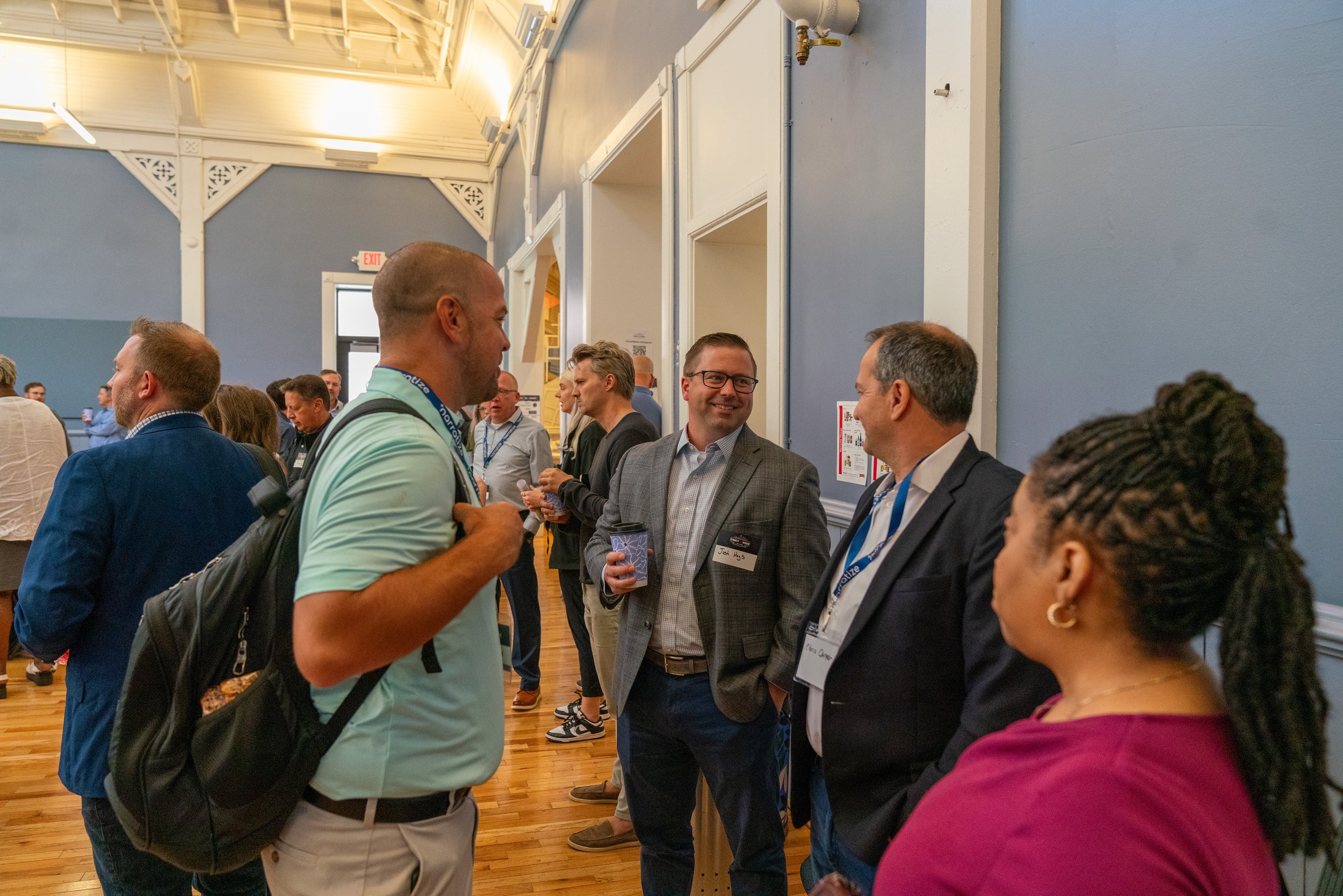 Group of diverse professionals engaging in conversation at a conference or networking event indoors.