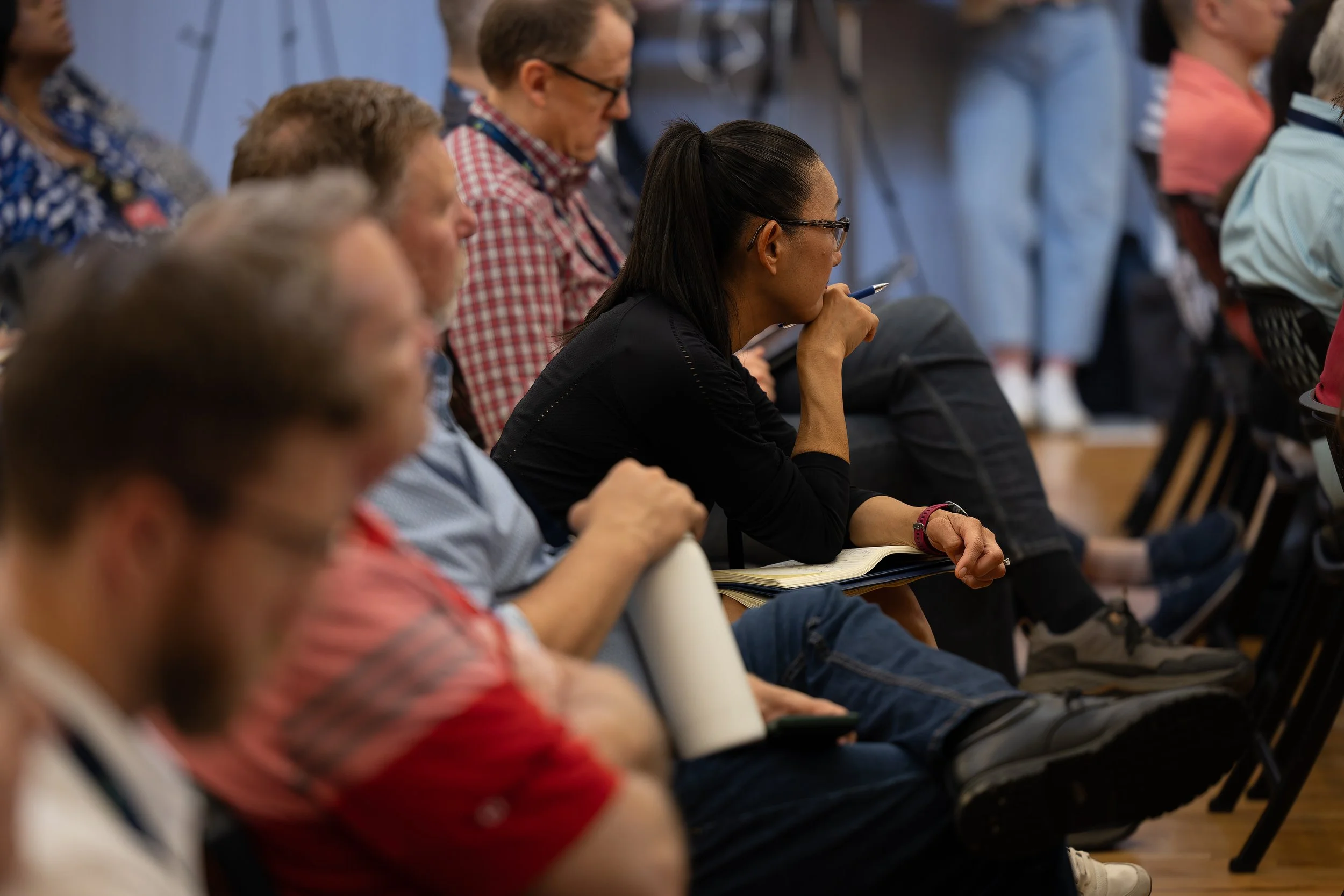 A silhouette of a person with curly hair holding a smartphone in front of a cityscape at night.