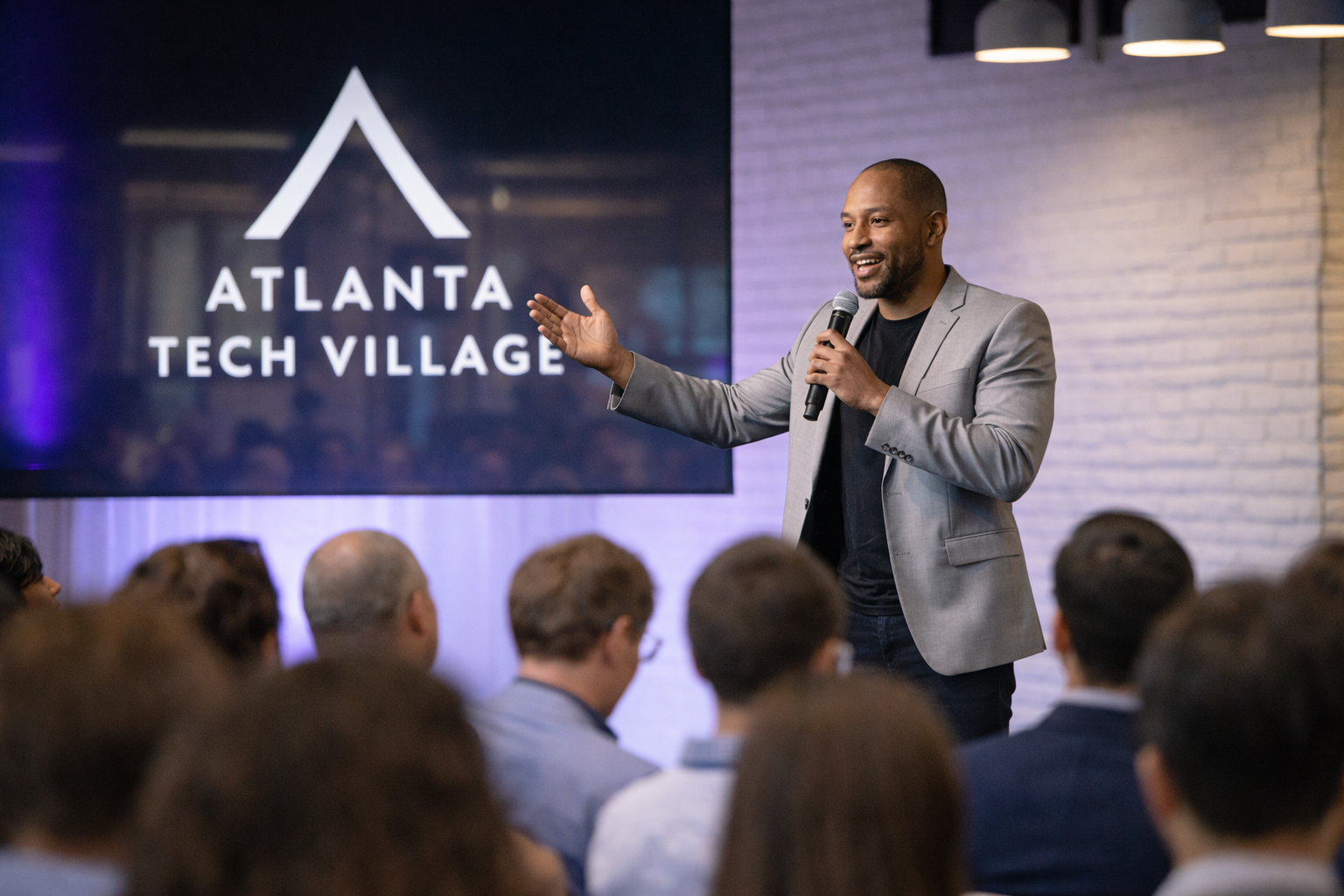 Four people sitting on a stage during a panel discussion, with balloons in the background and a presentation screen nearby.