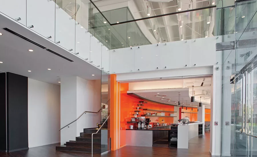 Modern cafe with orange accents and a curved counter inside a glass-front building.