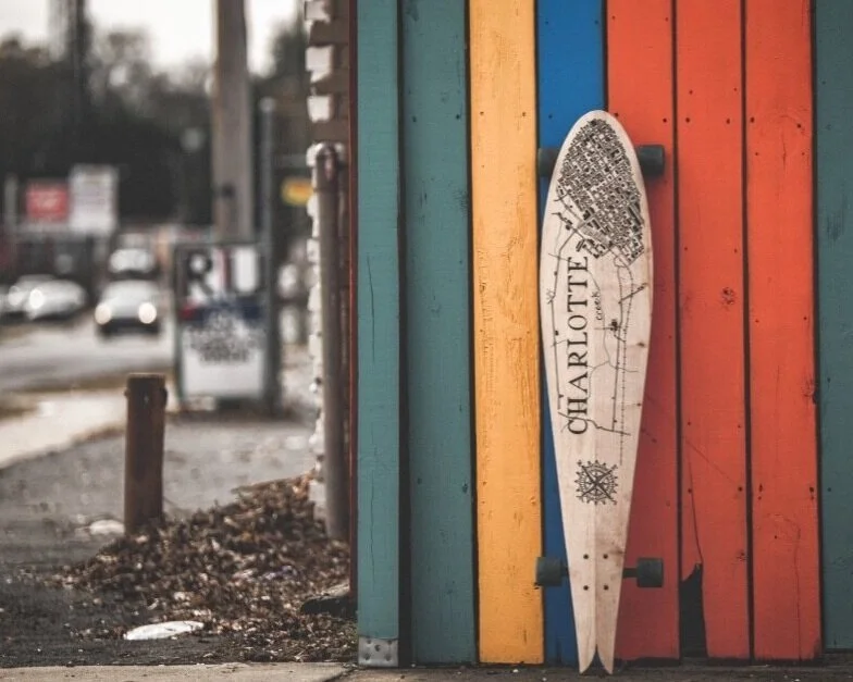 A skateboard leaning against a colorful wooden wall with blue, yellow, and red vertical planks.