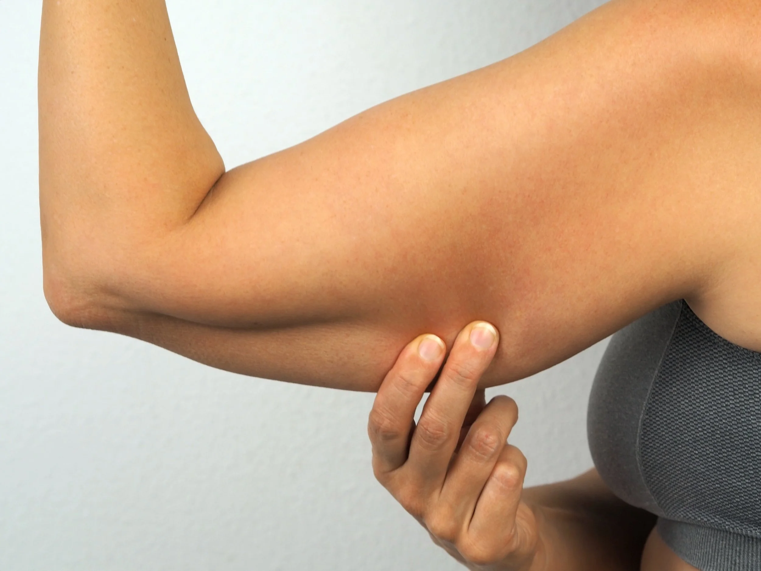 Close-up of a person's flexed arm showing the bicep muscle with one hand touching the inner elbow.