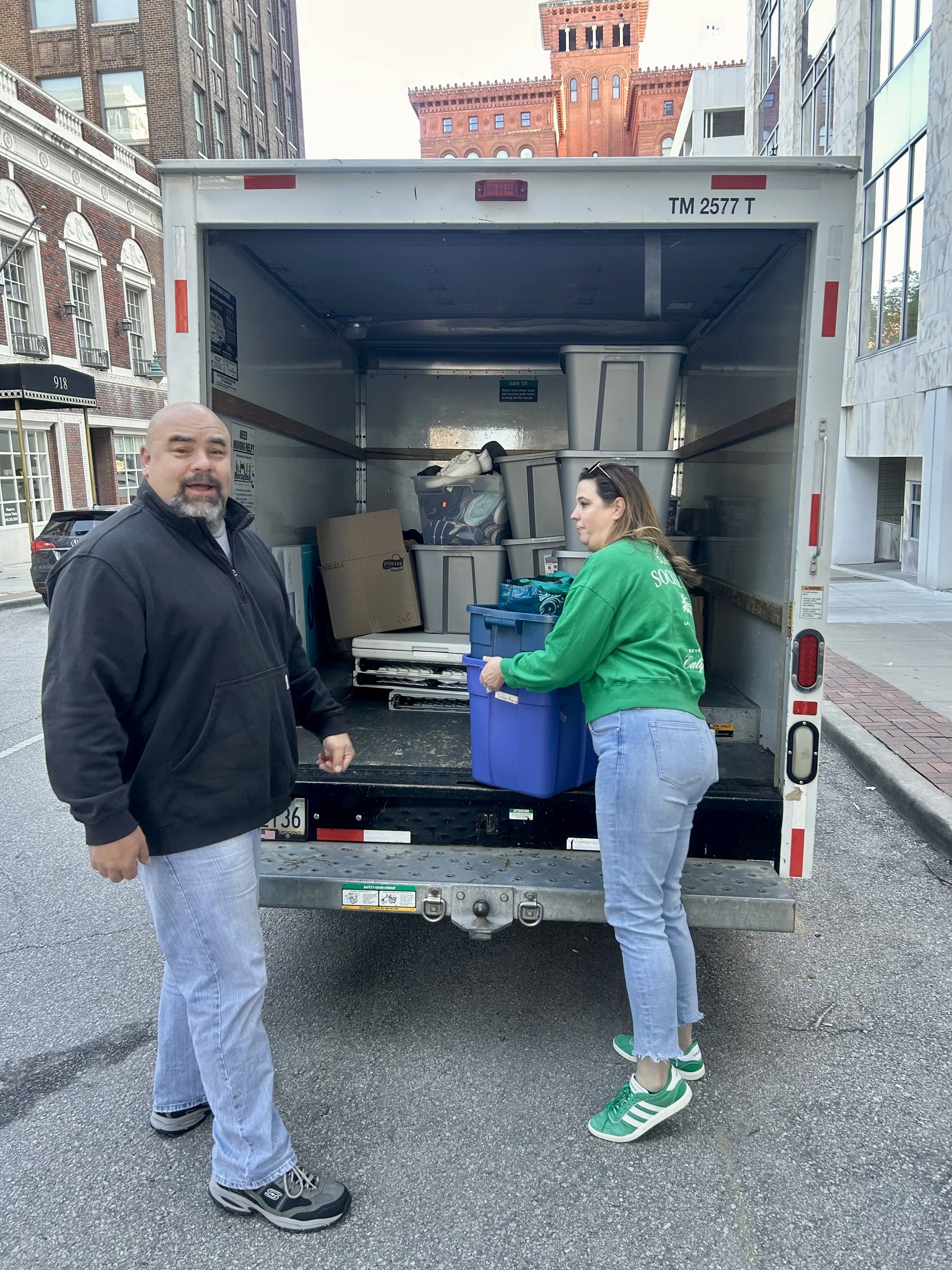 Man and woman loading moving boxes and plastic bins into a truck for Street Support KC.