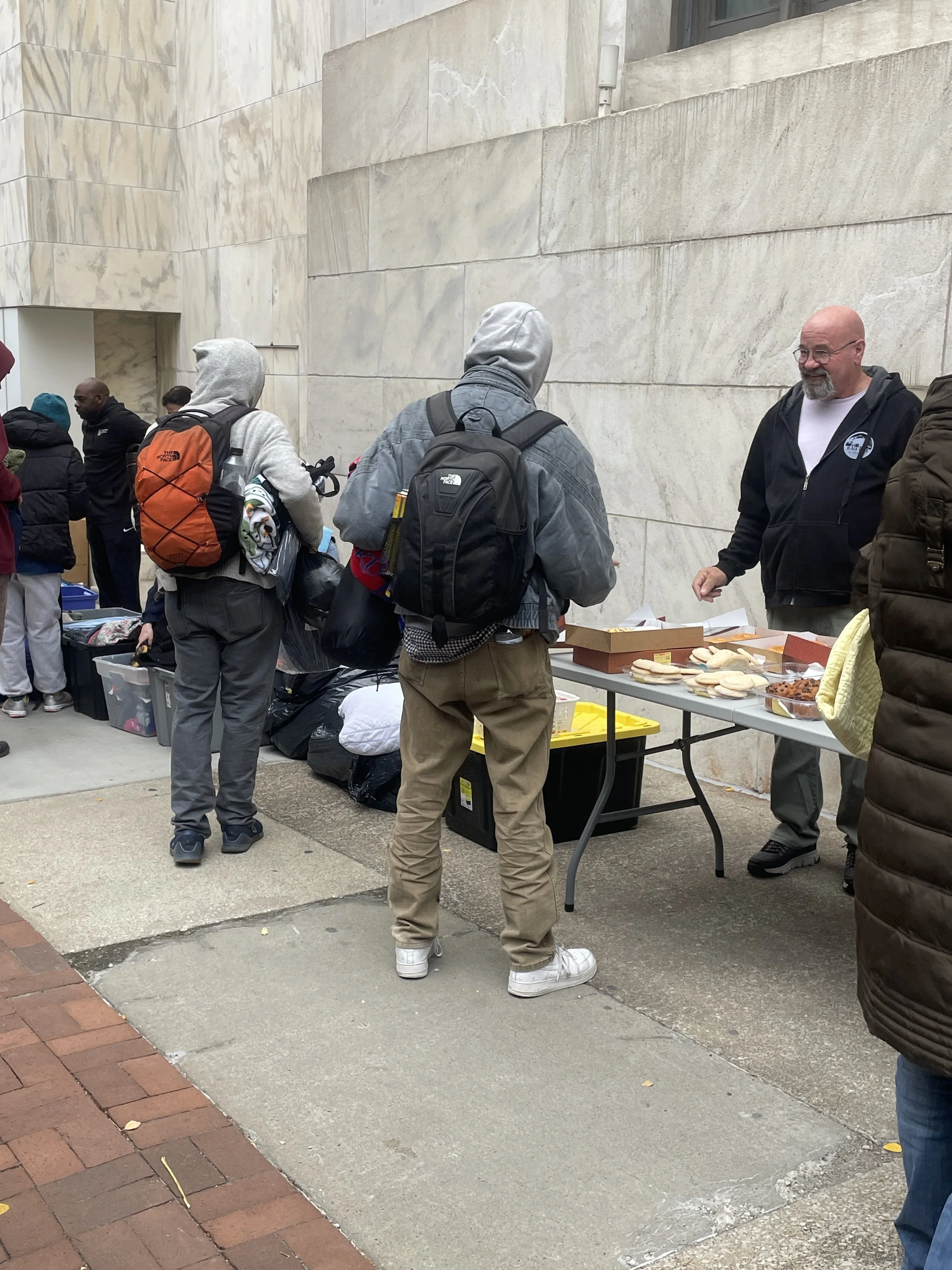 People gathered around a table with food outside for a Street Support KC event in Kansas City, Missouri.