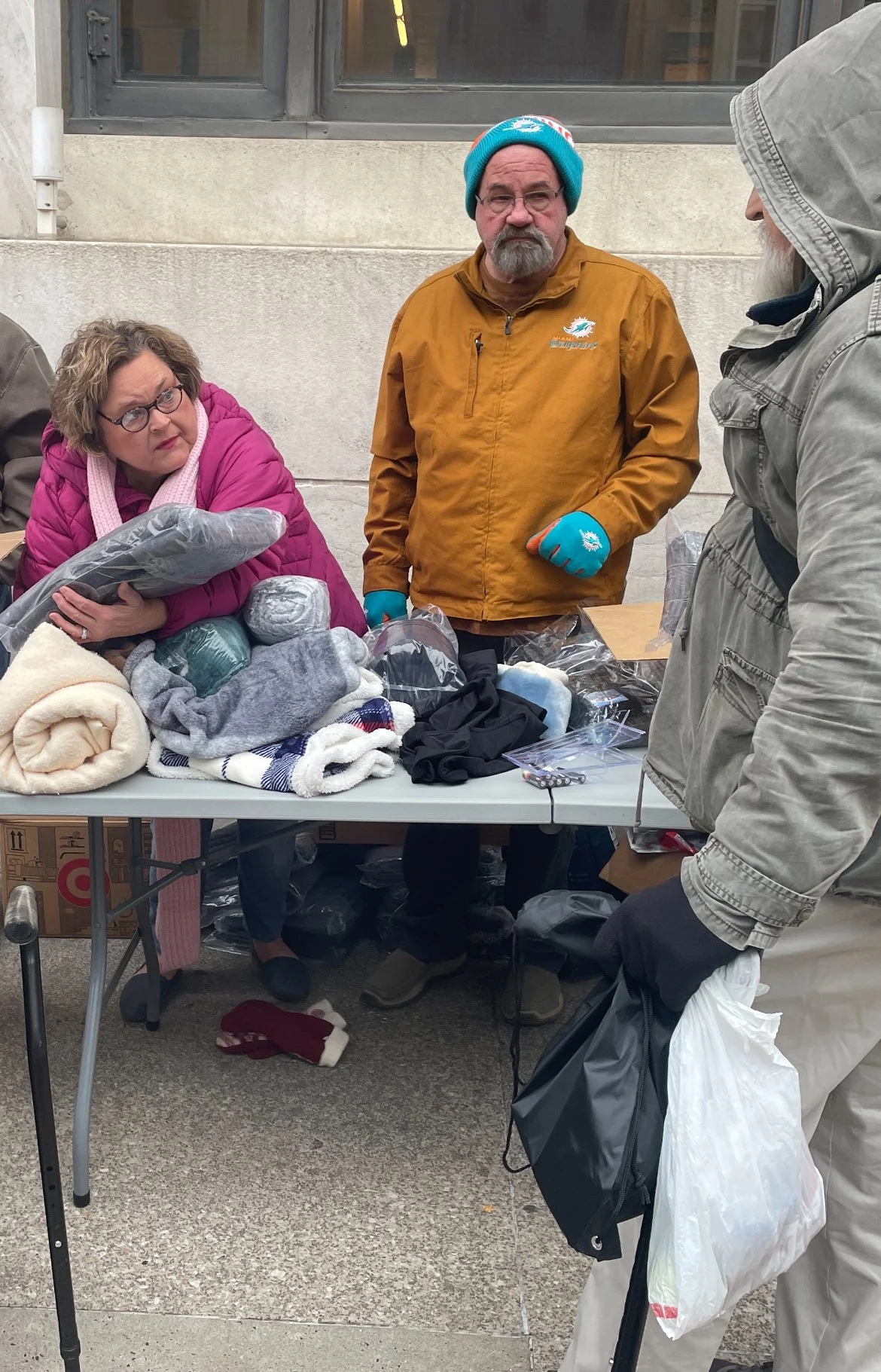 People at a Street Support KC table with various clothing items and accessories.