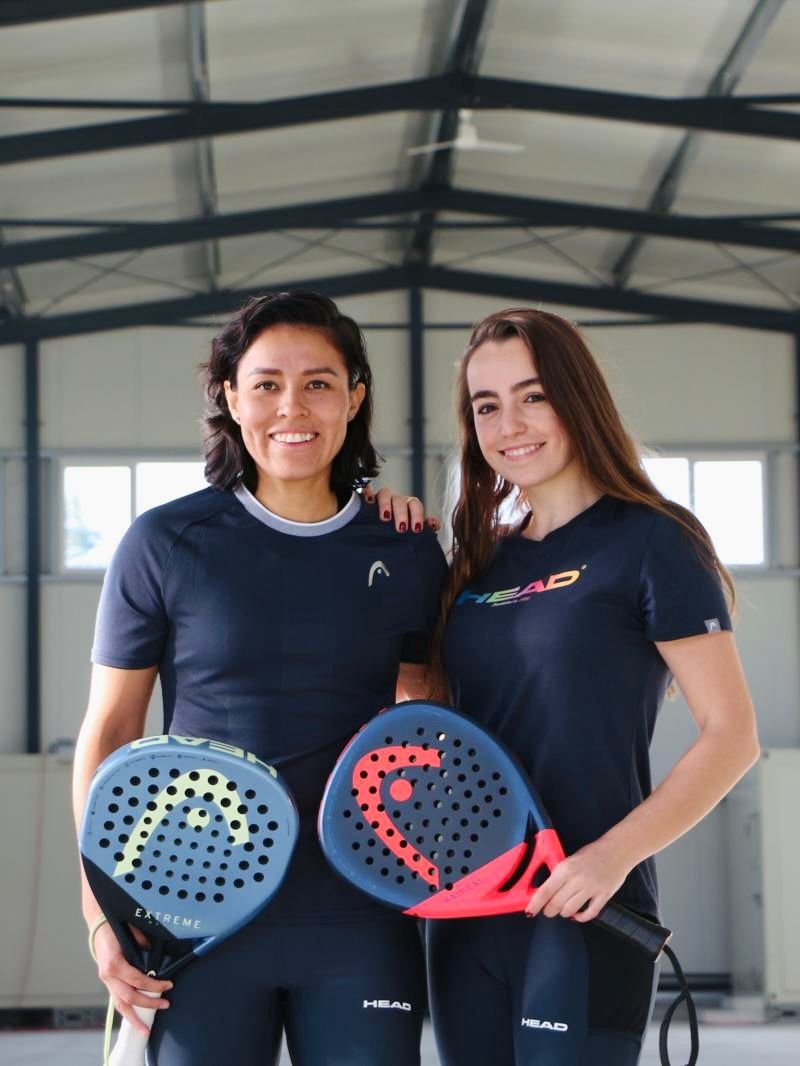 Nadia Acuña und Alex Alegre stehen in der Padel-Halle, halten Padel-Schläger und tragen Sportkleidung von HEAD.
