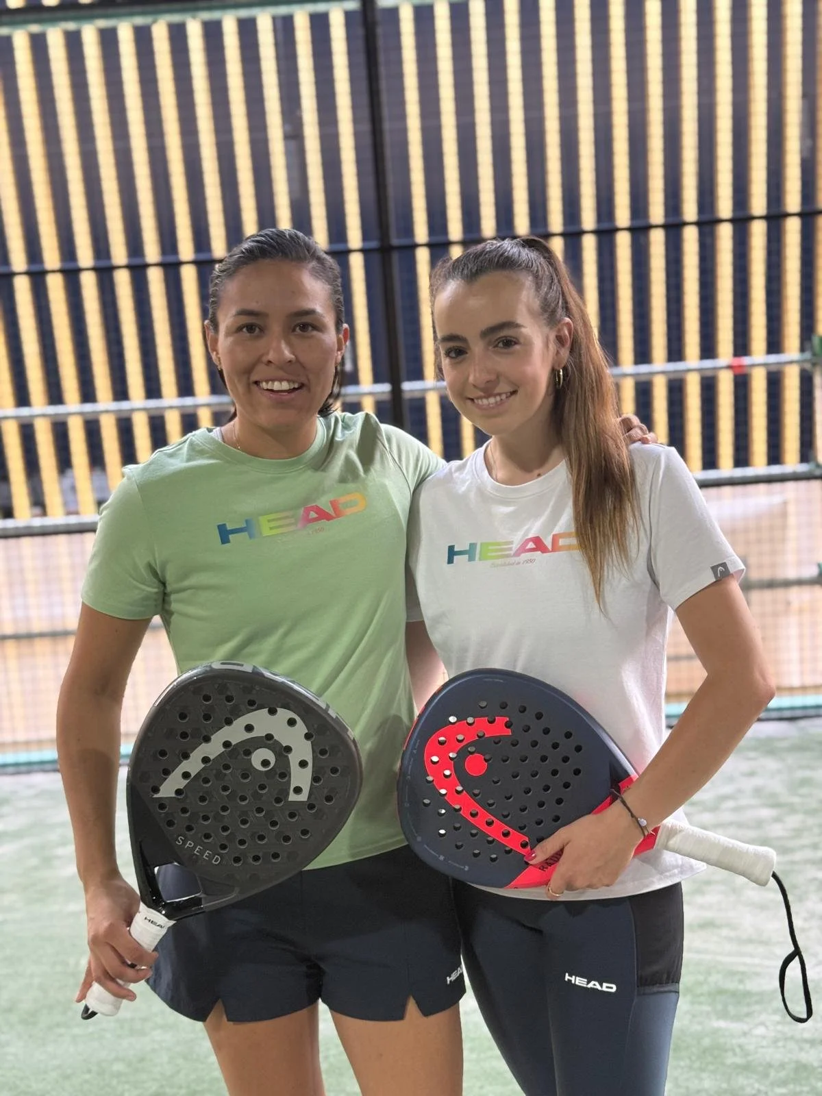 Nadia Acuña und Alex Alegre stehen auf einem Padelcourt, tragen Sportkleidung mit HEAD-Logo und halten Padelschläger in den Händen.