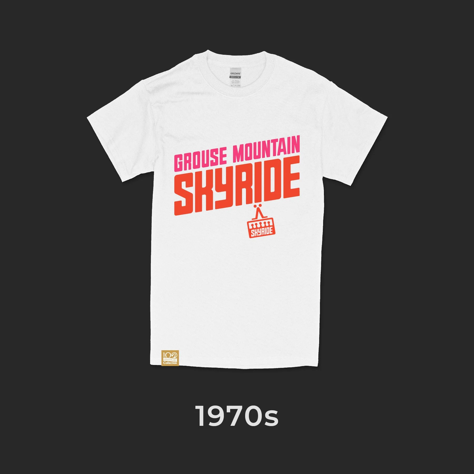 A white T-shirt with the text "Grouse Mountain Skyride" in pink and orange, featuring a small graphic of a gondola, against a black background. The bottom left corner of the shirt has a small gold label, and the text "1970s" is displayed below the shirt.