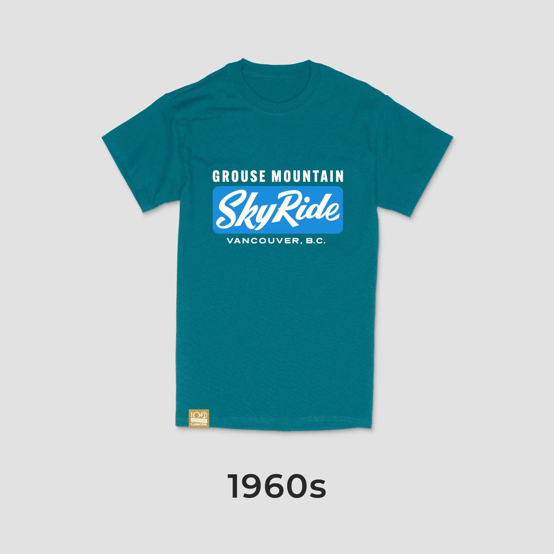 A vintage 1960s teal T-shirt with white and blue text reading 'Grouse Mountain SkyRide Vancouver, B.C.' and a small gold label at the bottom left.