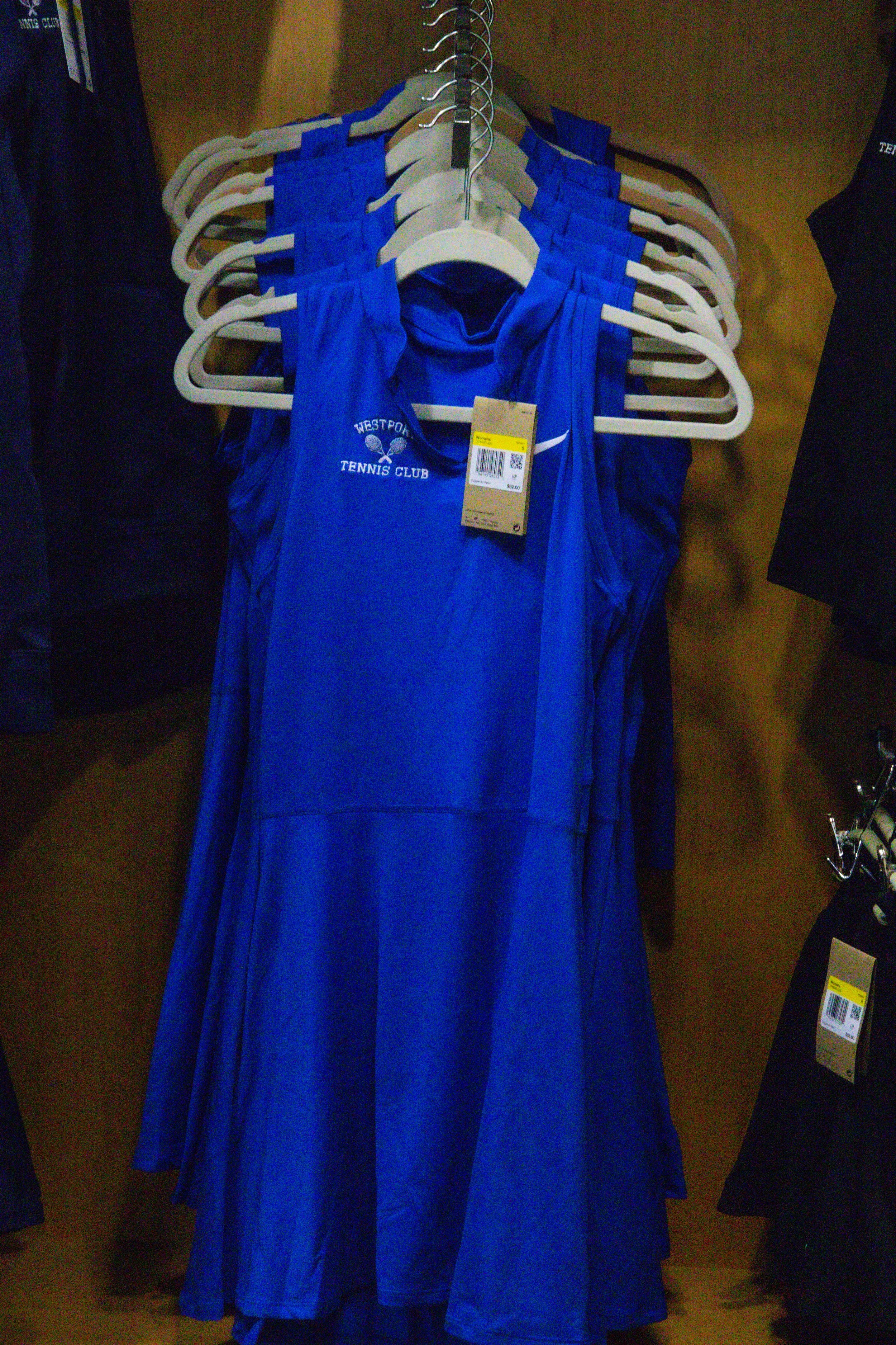 Women’s blue Westport Tennis Club tennis dress hanging on rack inside the club’s pro shop.