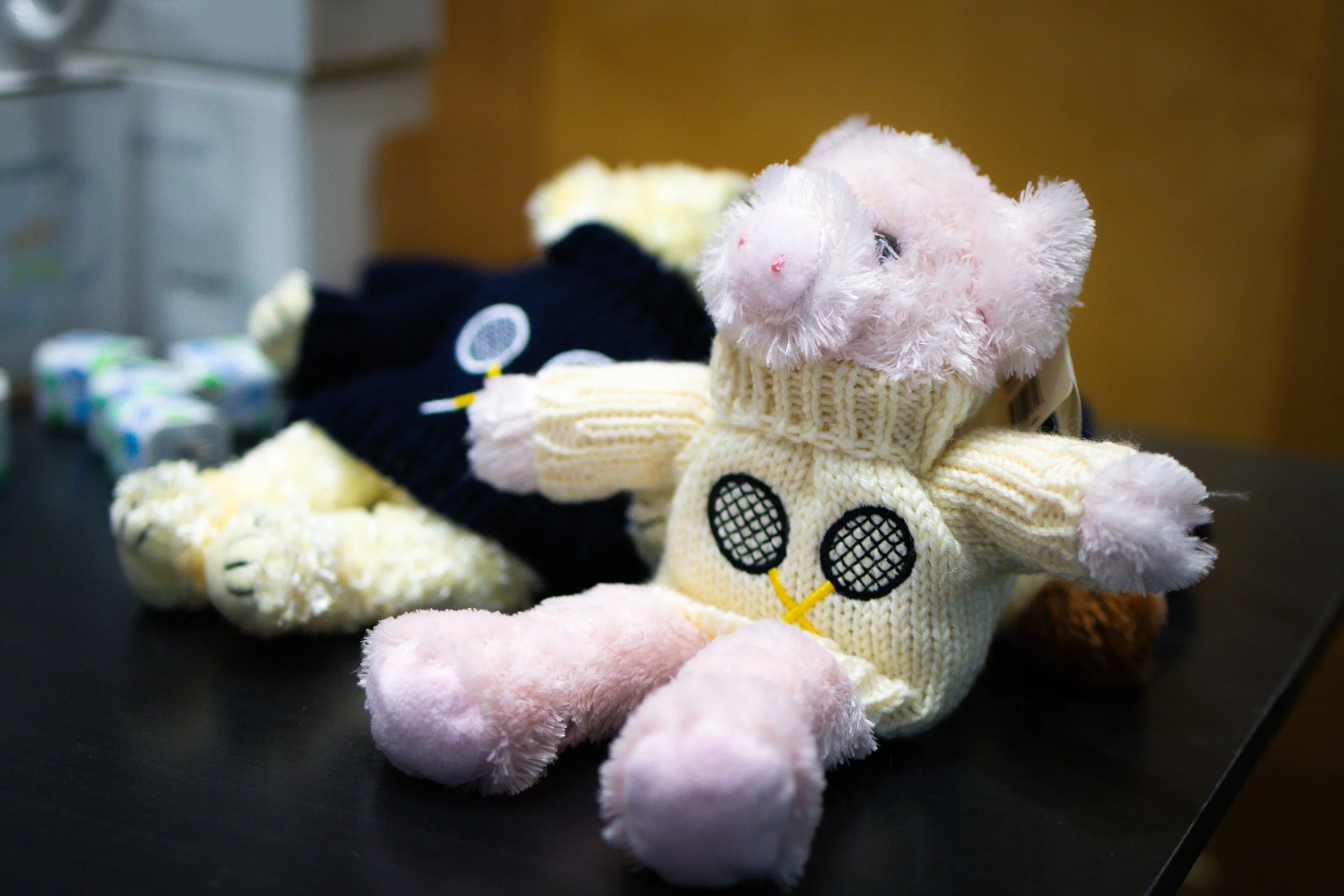 Plush toy collection at Westport Tennis Club pro shop, including a pig in a knit sweater with tennis racket design.