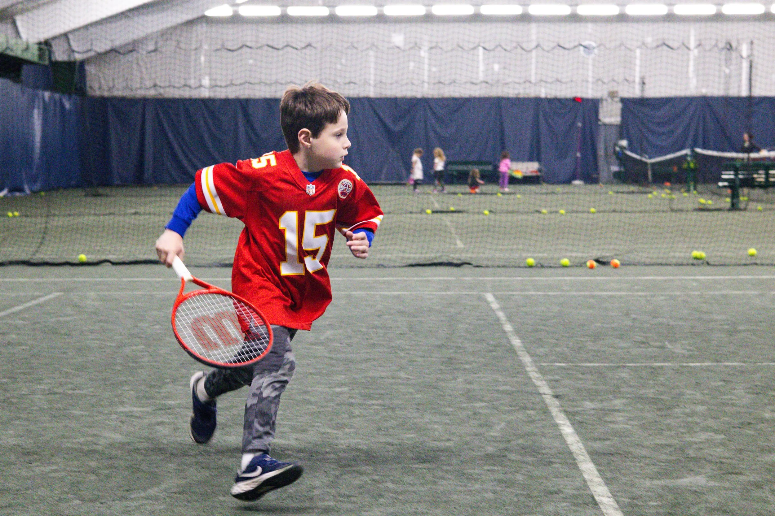 Junior tennis player running on the indoor courts at Westport Tennis Club during kids’ drills and games.