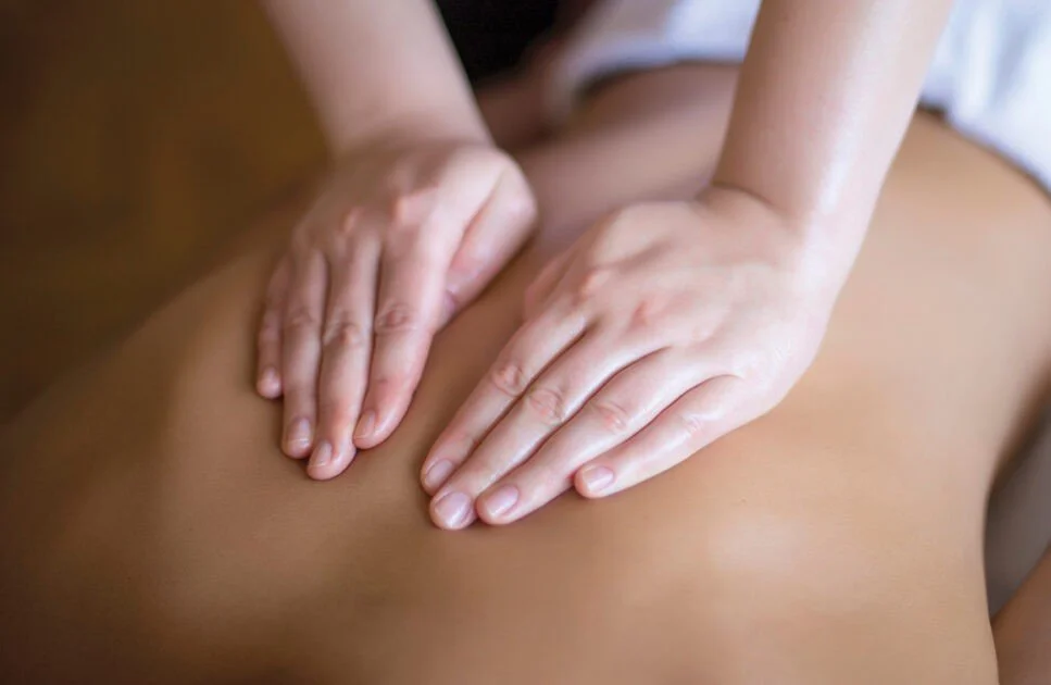 Close-up of a person giving a massage on a person's back with their hands.