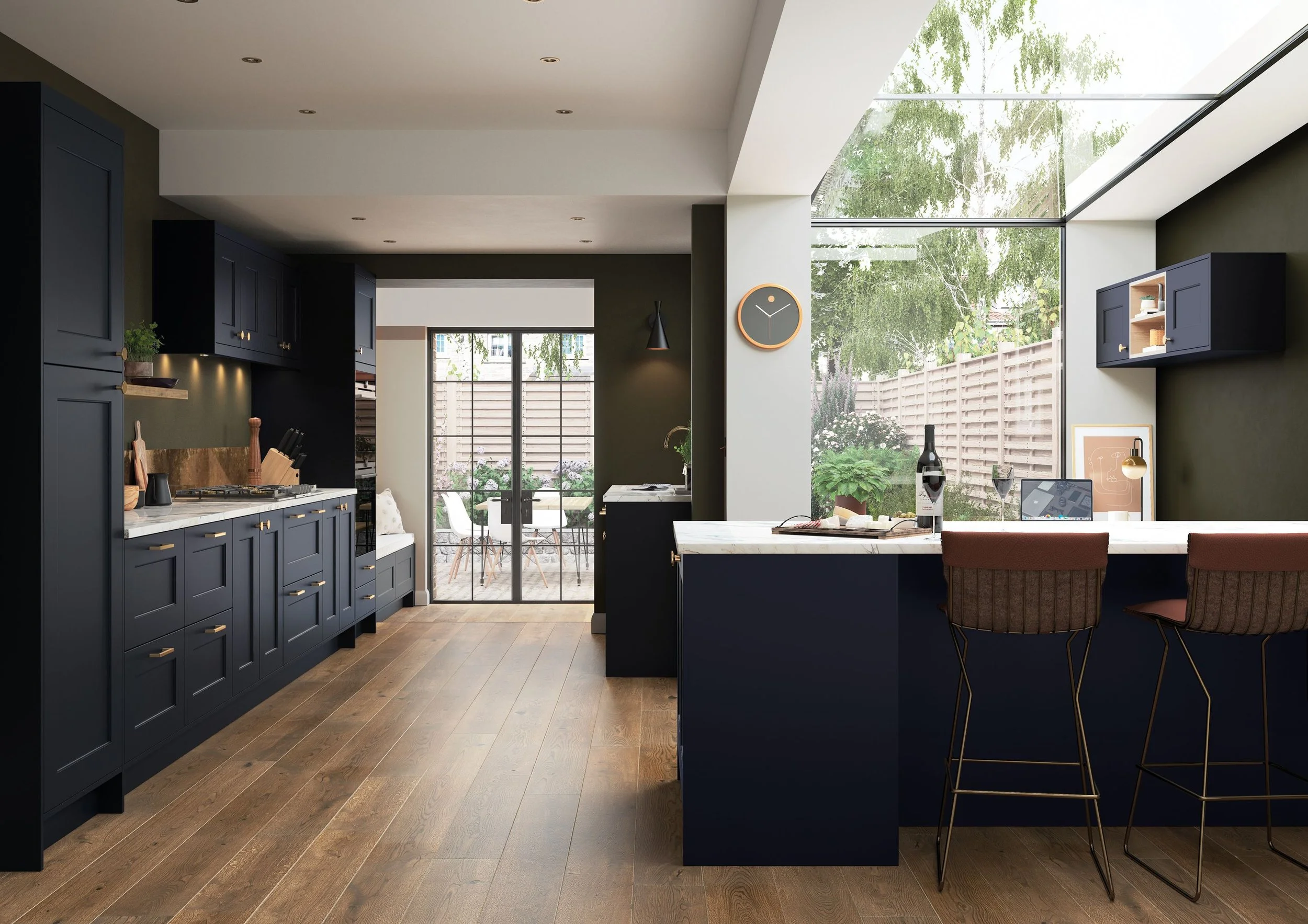 Modern kitchen with navy blue cabinets, white marble countertops, and wooden flooring. A kitchen island with two brown bar stools, a bottle of wine, and a laptop. Large window and sliding glass door leading to an outdoor patio with trees and garden.