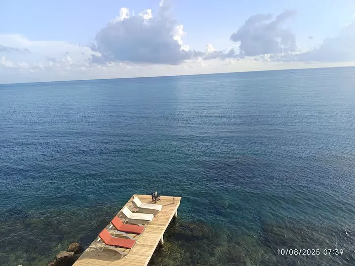 Waterfront Dock with lounge Chairs over calm Caribbean Sea.
