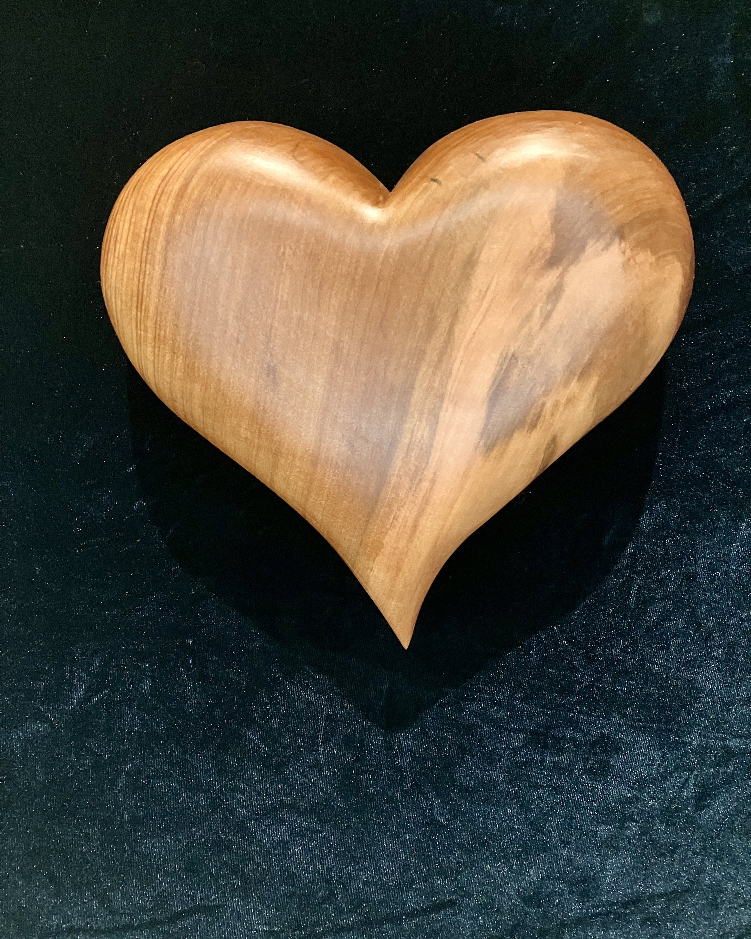 A wooden heart-shaped object on a black surface.