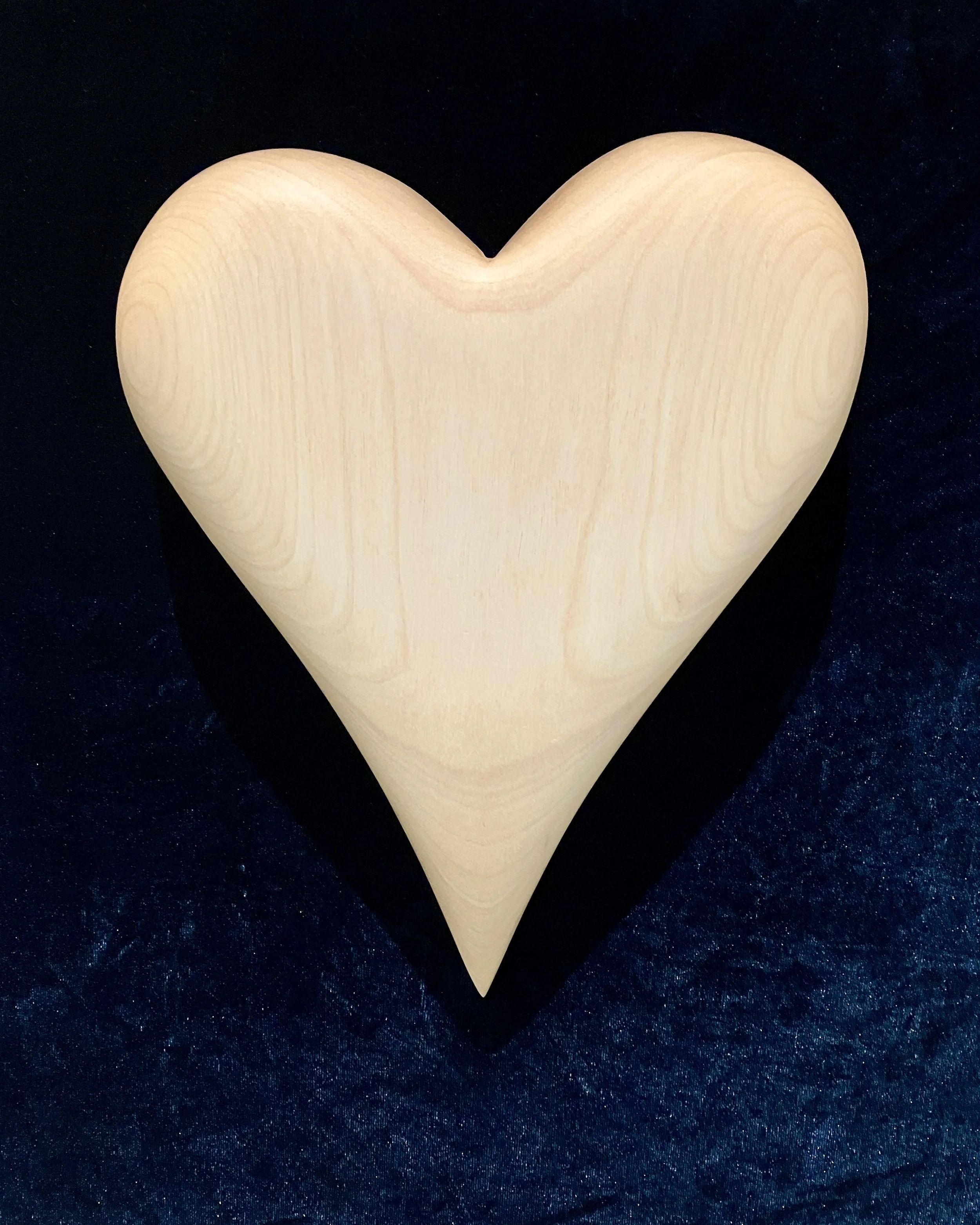 A light-colored wooden heart on a dark textured background.