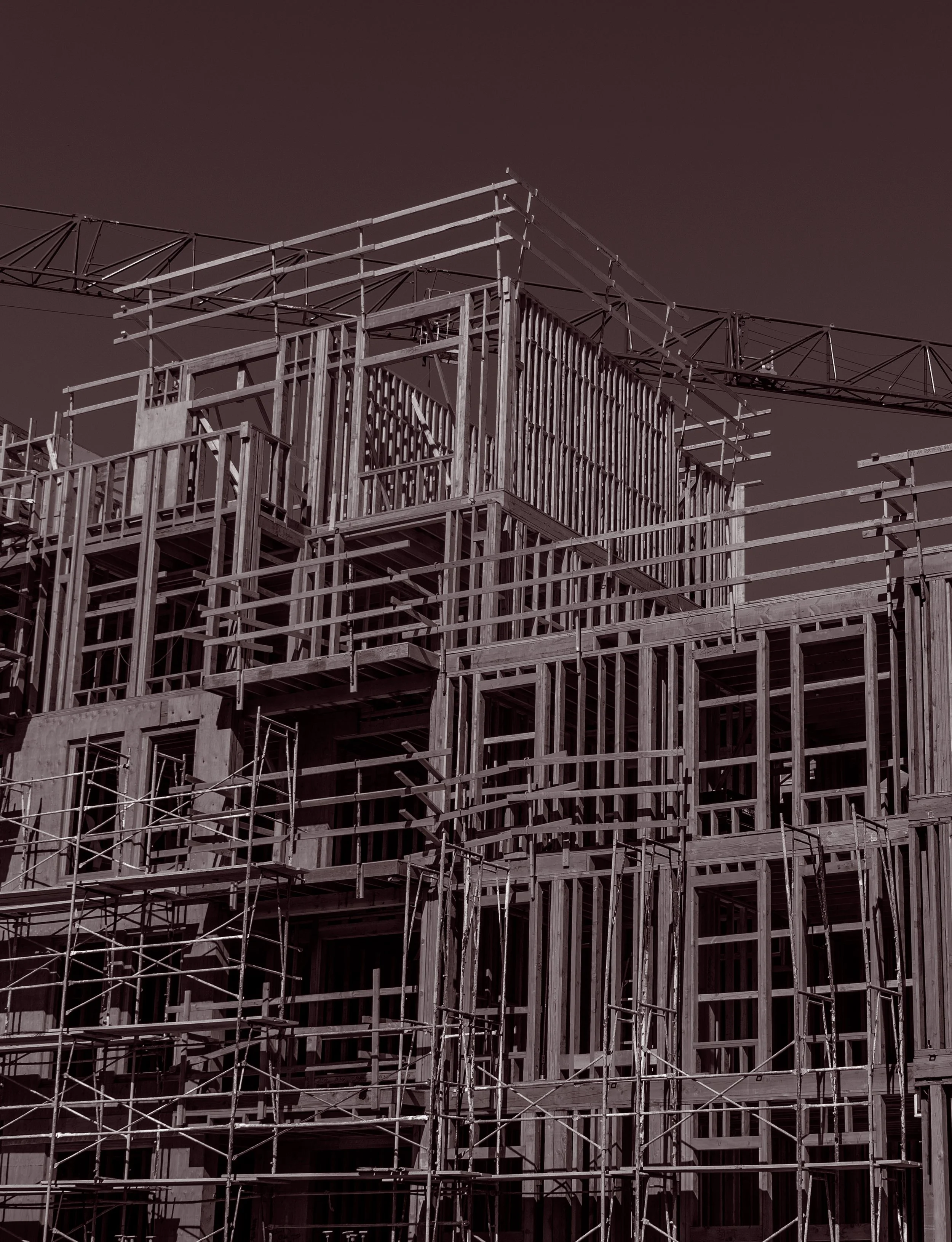 A multi-story building under construction with exposed wooden framework and scaffolding.