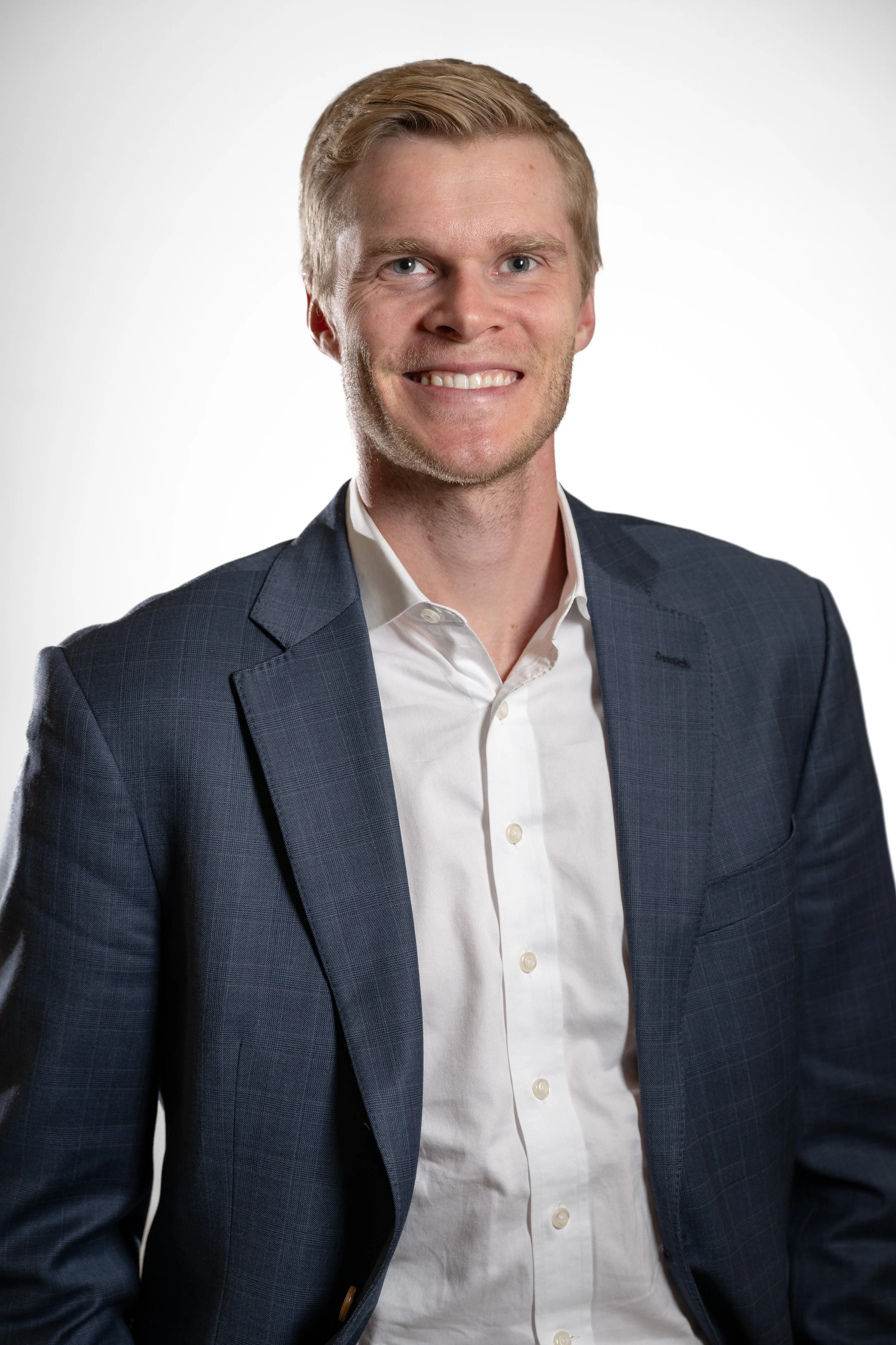 blonde smiling man with a suit jacket and white background