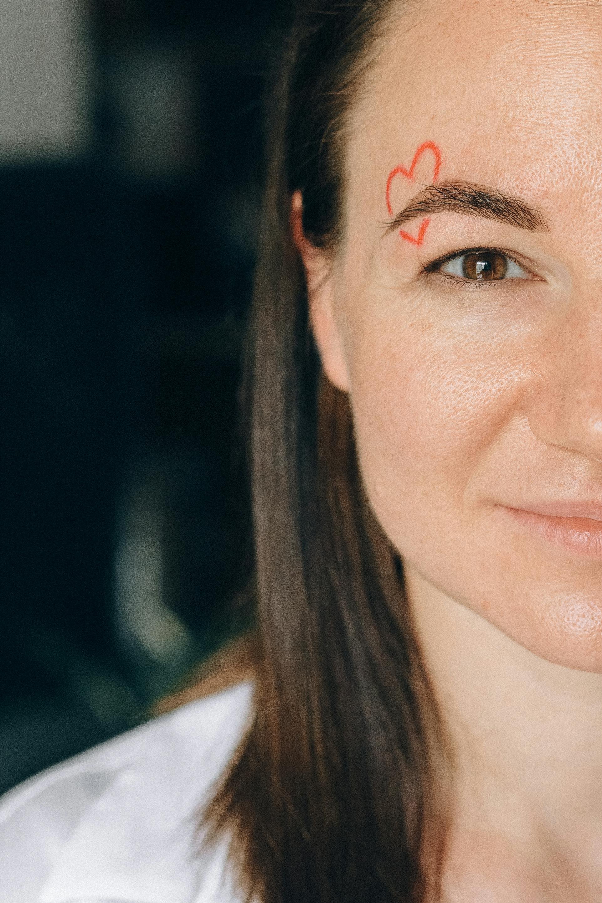 Close-up of a female trauma survivor's face with a bandage on their cheek labeled 'HOPE', decorated with yellow and pink flowers.