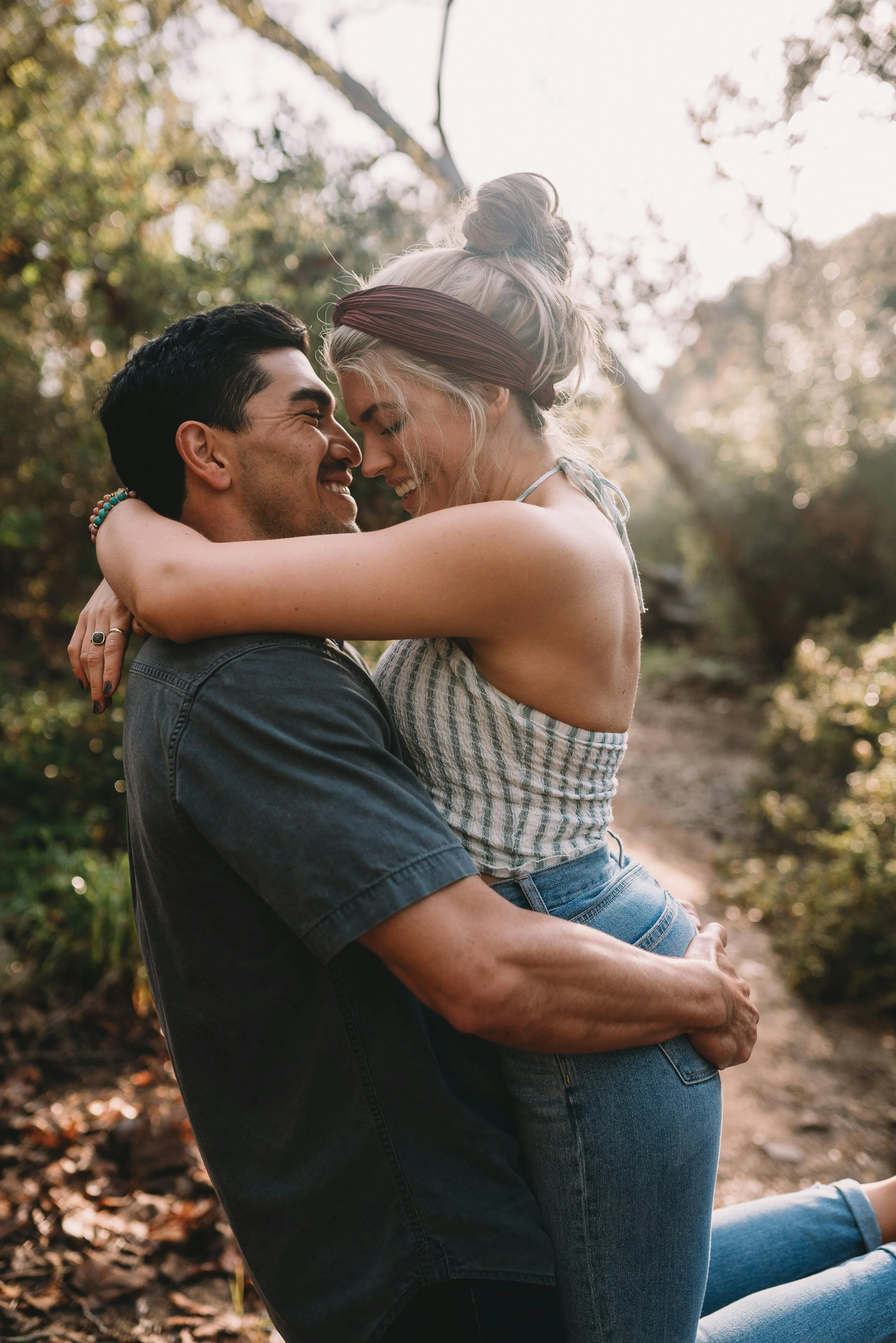 A happy Dallas couple stands close together after couples therapy on a rocky beach at sunset, smiling and embracing each other.