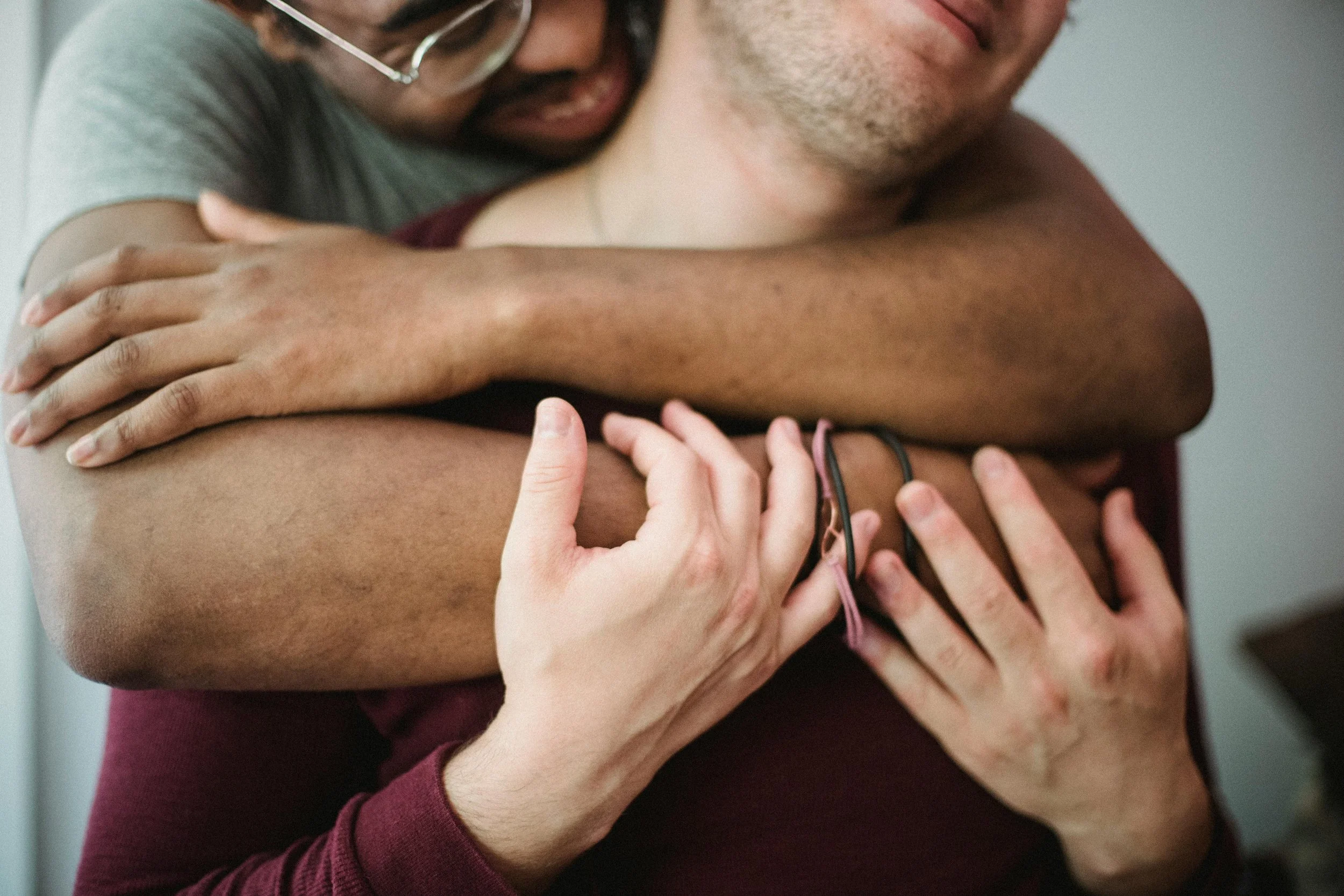 Two people hugging tightly, one with darker skin and the other with lighter skin, showing an emotional moment of comfort and support after Dallas couples therapy.