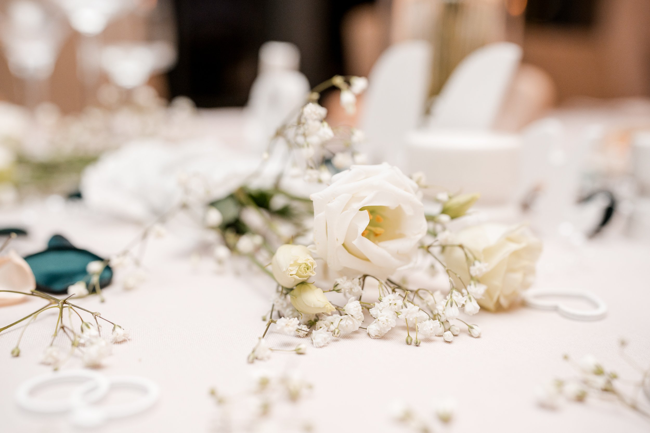 Weiße Blumen und Trockenblumen auf einem Tisch bei einer Feier oder Hochzeit, unscharfer Hintergrund.