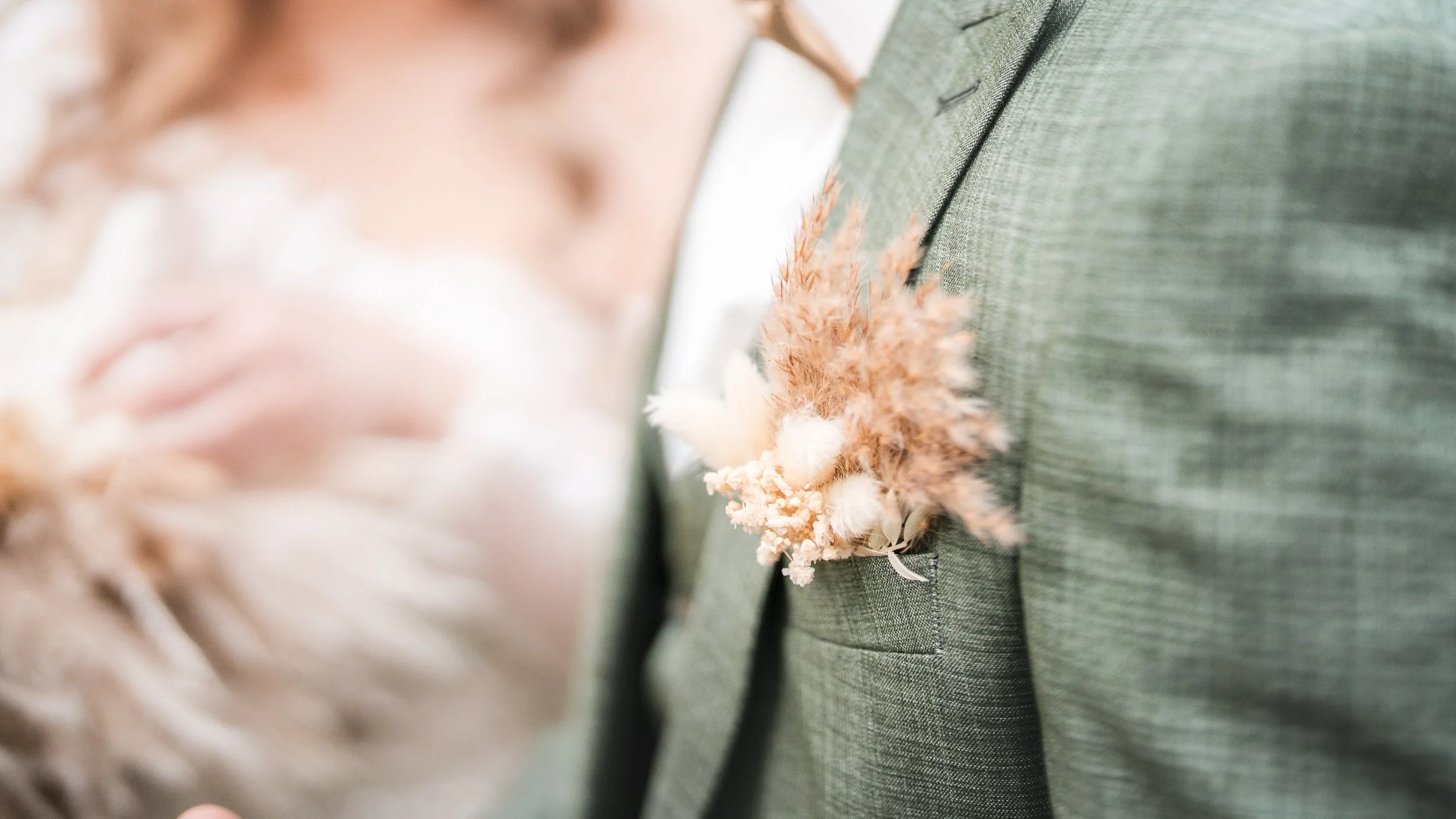 Nahaufnahme eines Hochzeitsanzugs mit Blumenanstecker auf der Brusttasche.