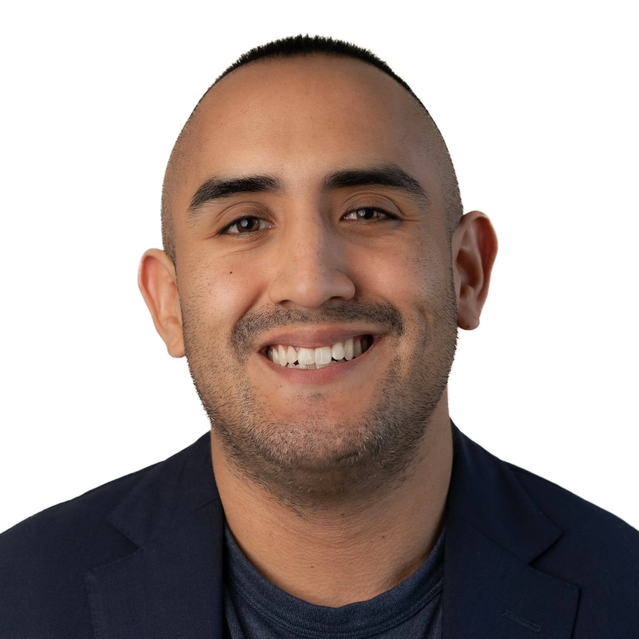 Close-up portrait of a smiling man with short hair, dark shirt, and a dark blazer against plain white background.