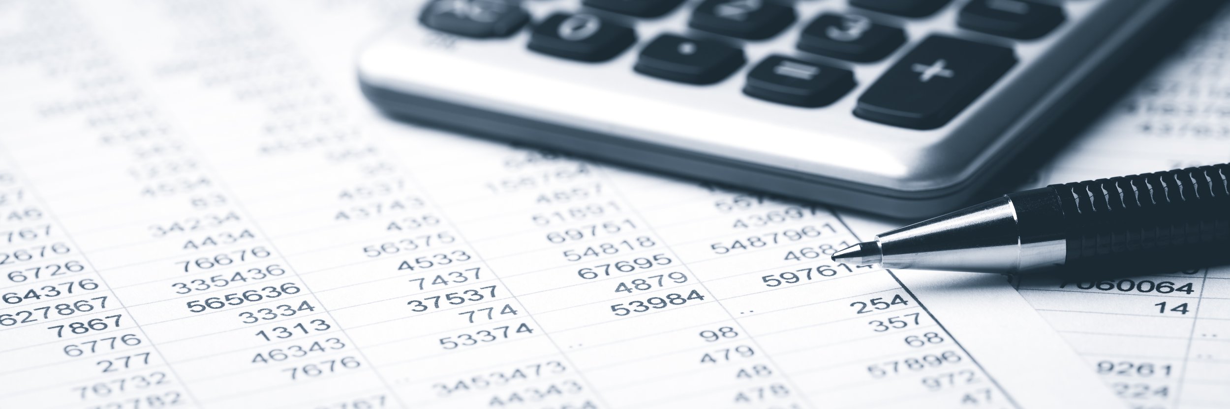 Close-up view of a calculator, pen, and printed spreadsheets or financial documents with columns of numbers.