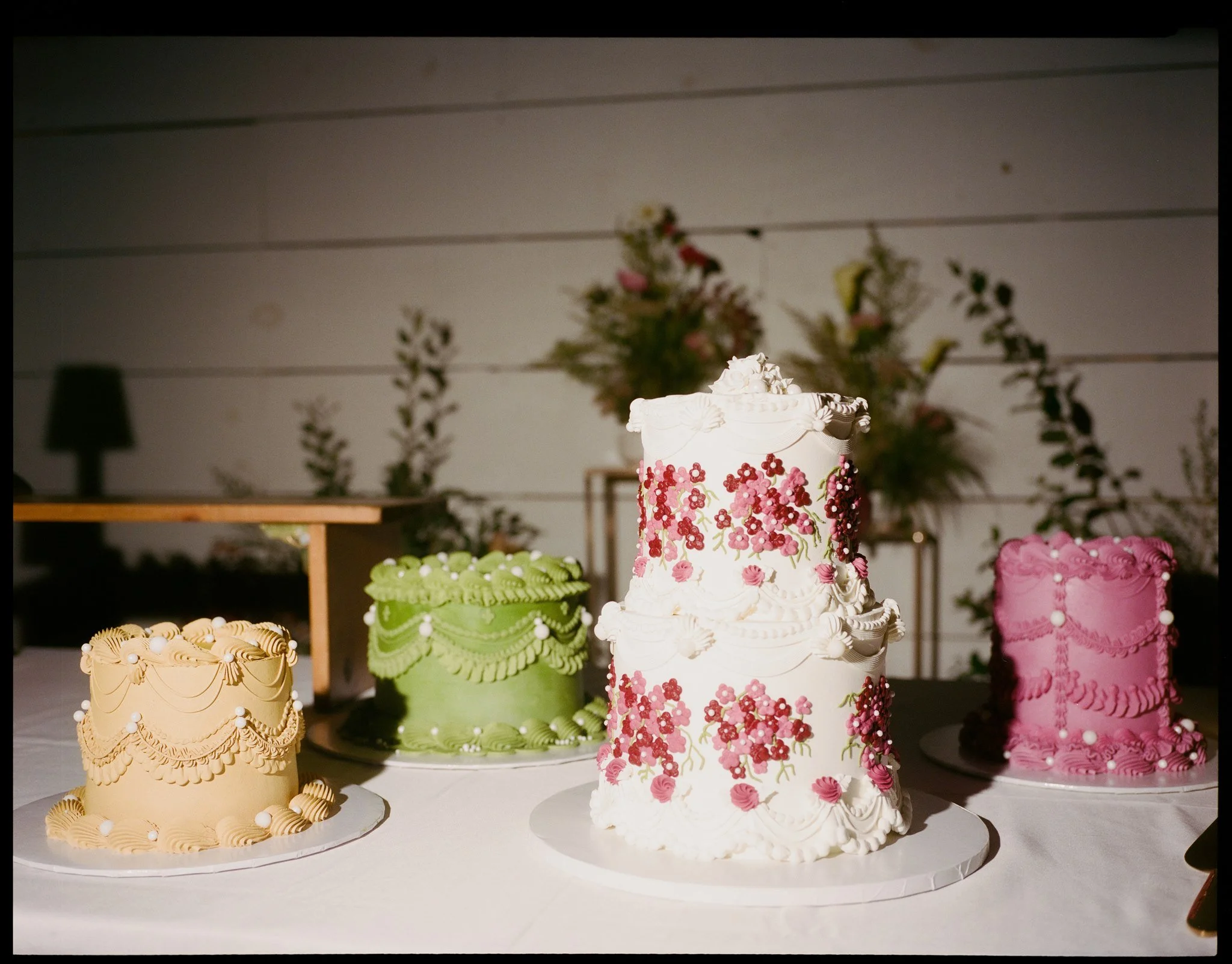 Decorative cakes with floral and ruffled designs displayed on a table.