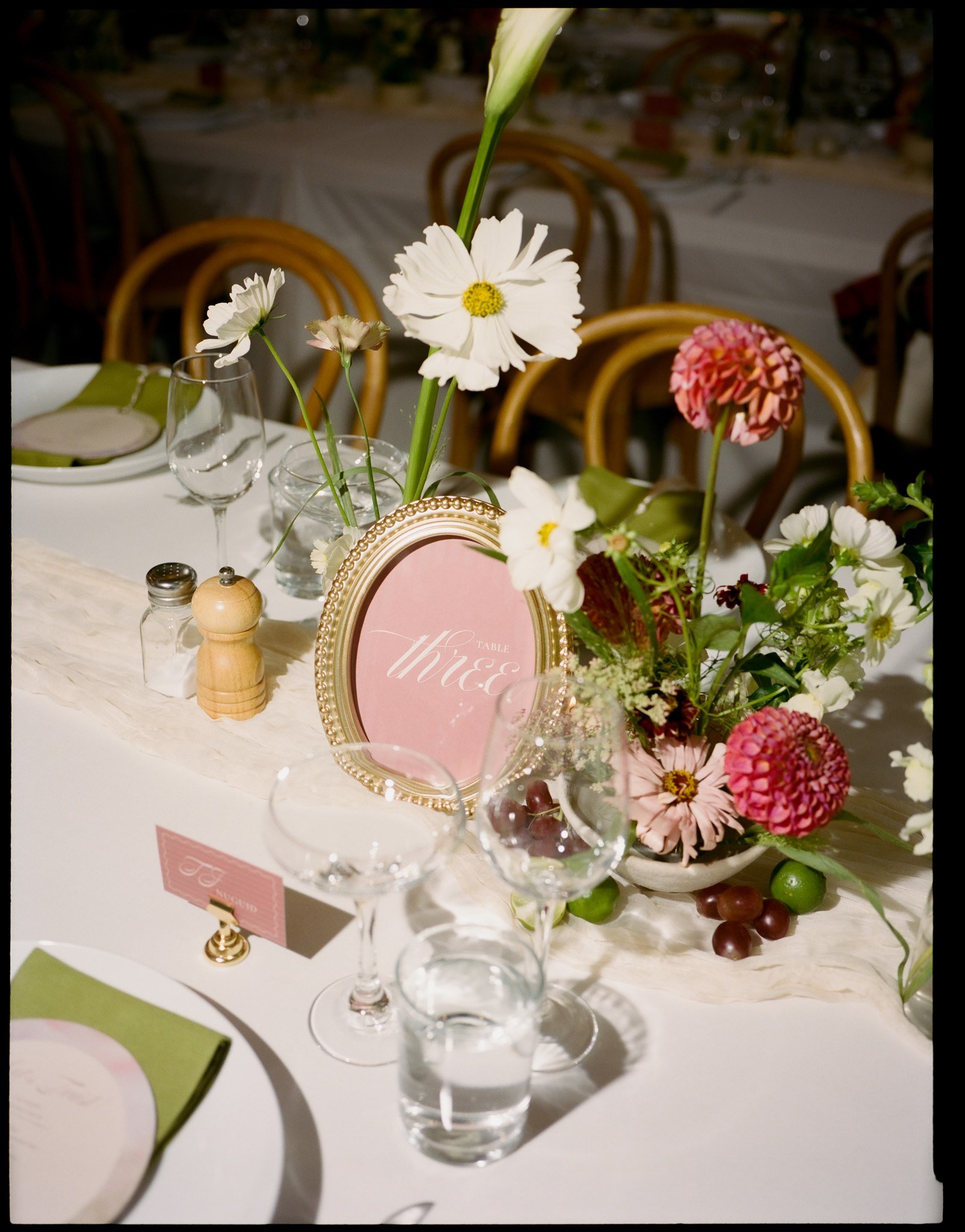 A table decorated with flowers, a pink framed sign, and glassware, set for a celebration or event.
