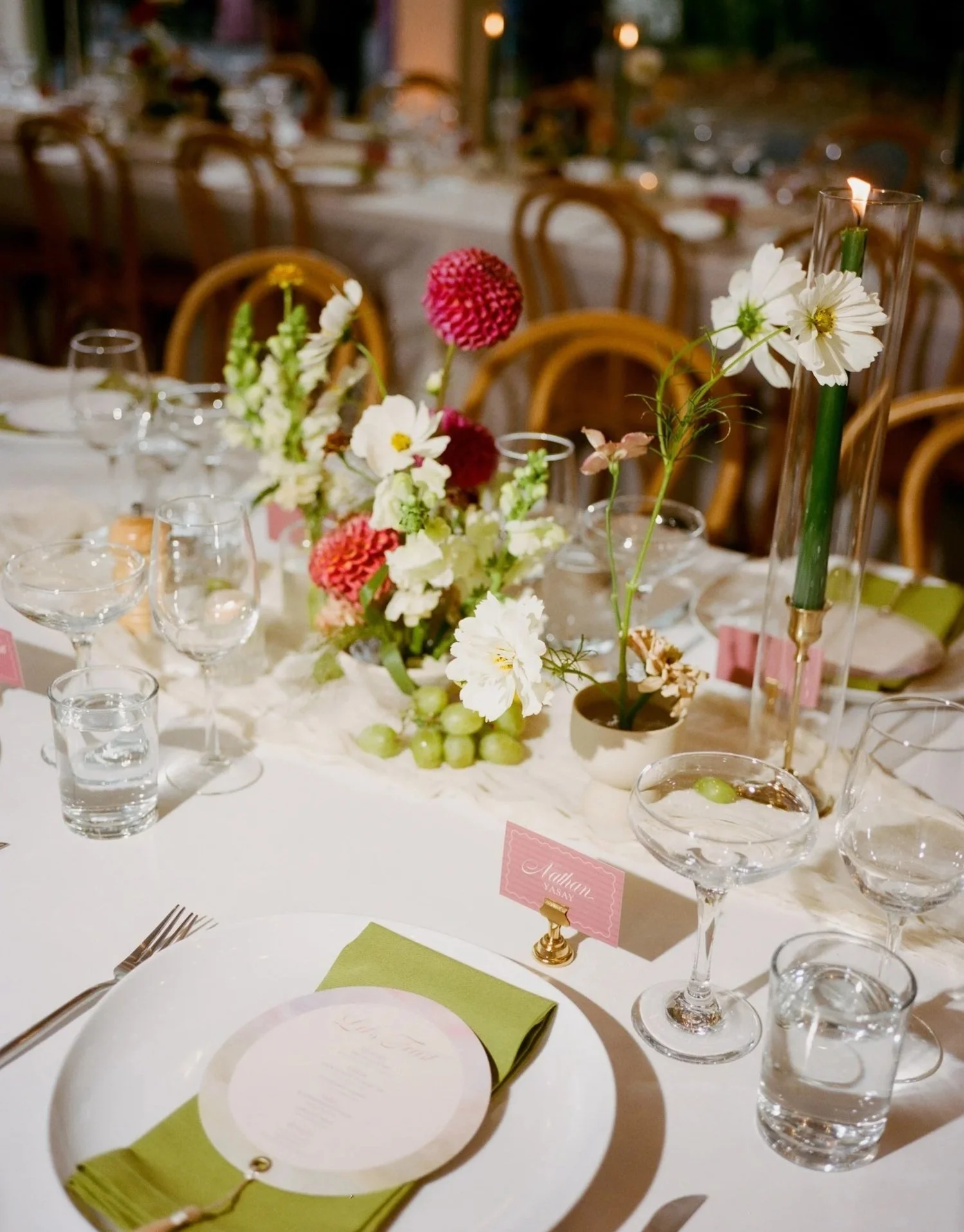 A decorated banquet table with floral centerpieces, wine glasses, water glasses, plates, and utensils, set for a formal event or wedding reception.