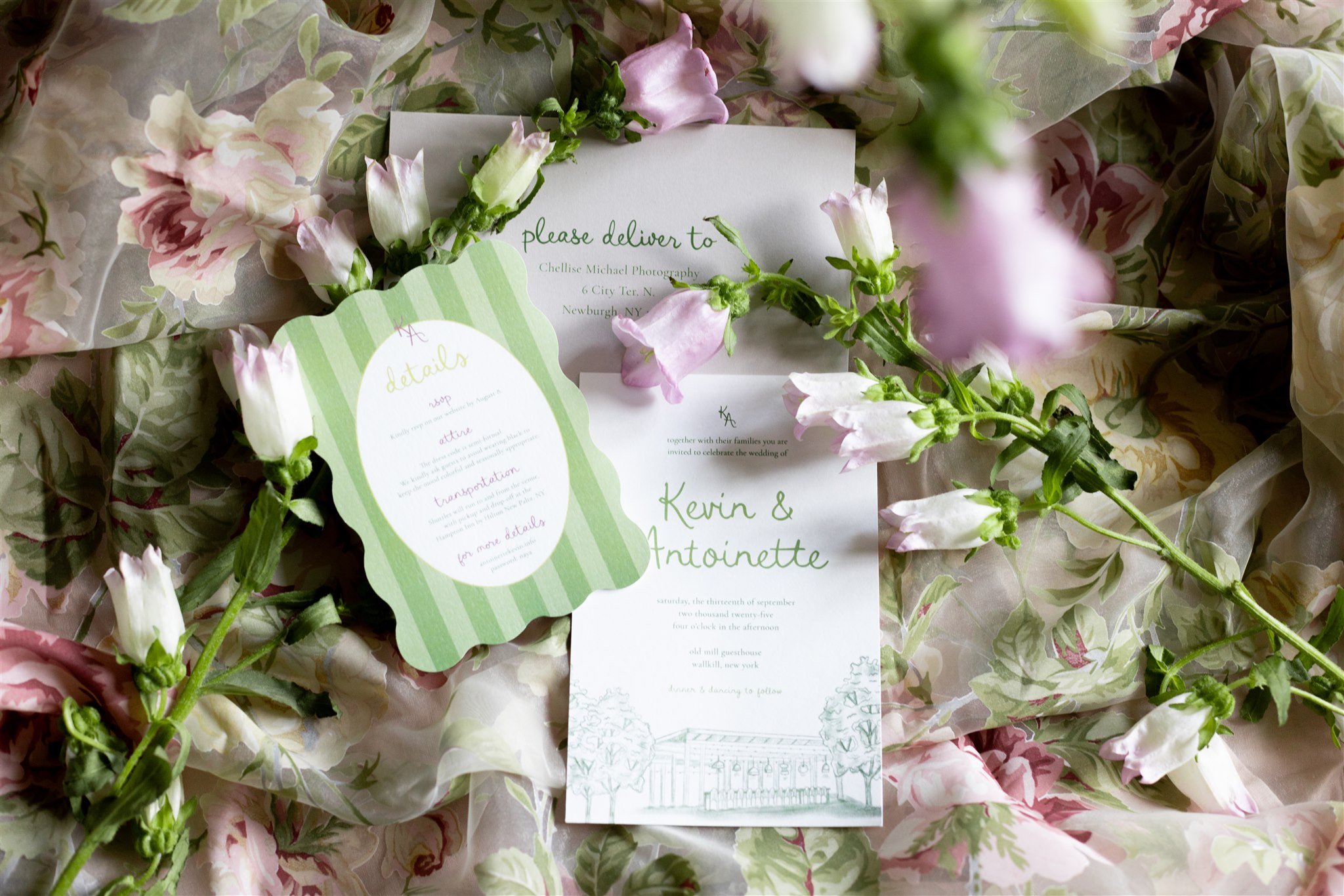 A wedding invitation surrounded by pink and white flowers on floral-patterned tissue paper.